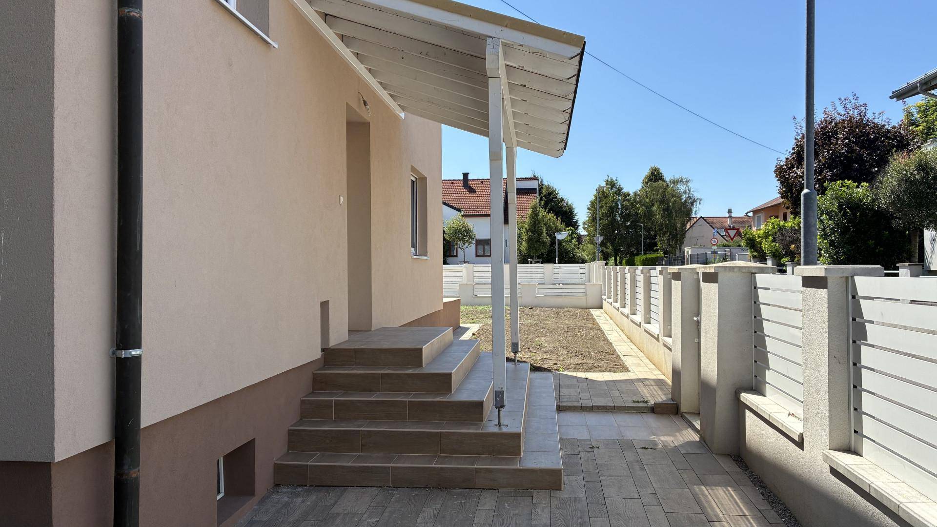 Eingangsbereich des Hauses mit überdachtem Vordach und gepflastertem Weg zum Garten.