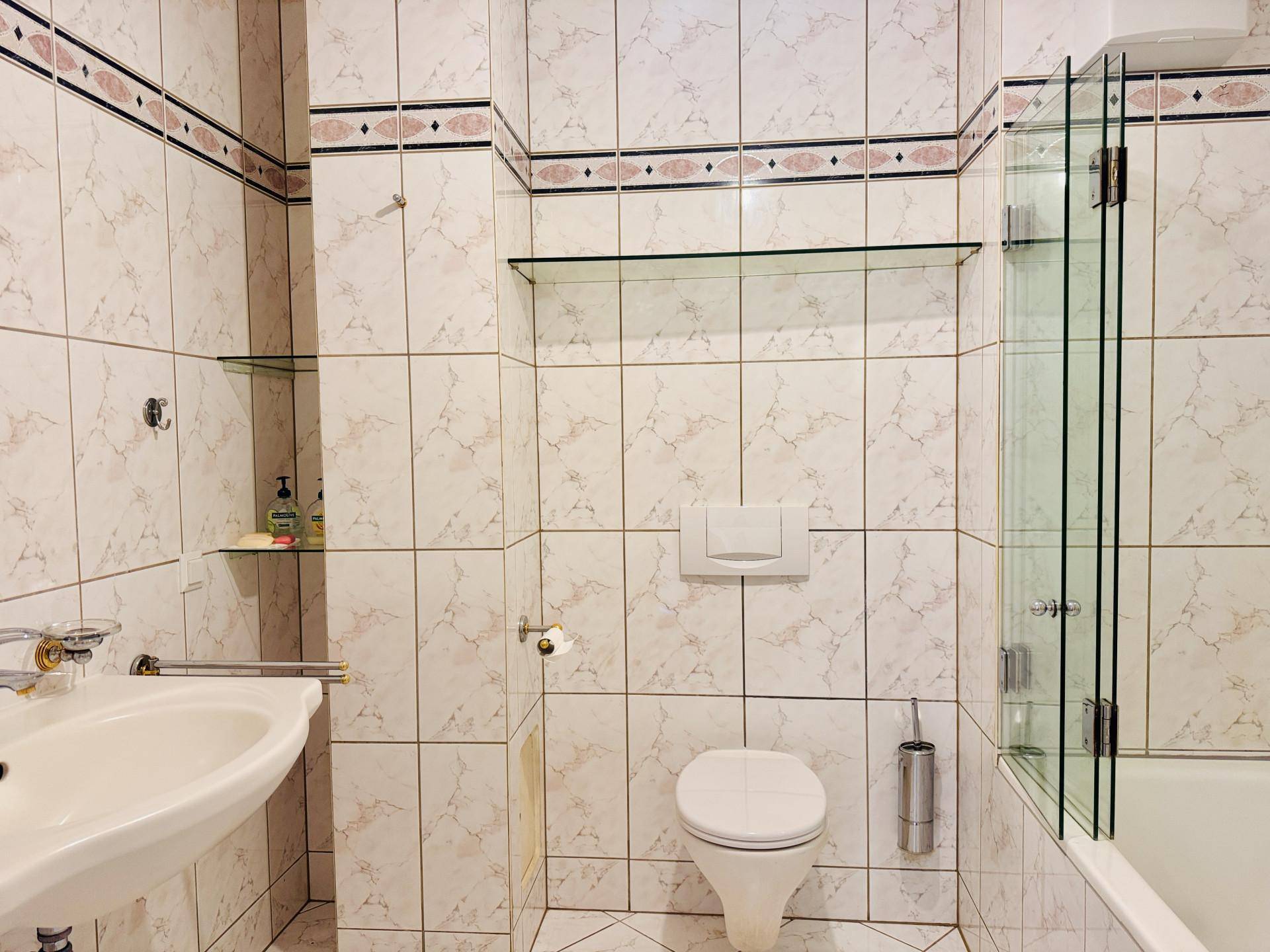 Gefliestes Badezimmer mit Badewanne, Dusche und WC in einem klassischen Design.