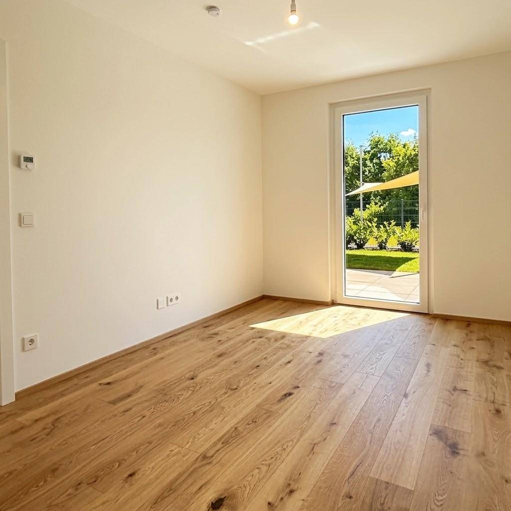 Helles Zimmer mit Holzboden und Zugang zu einem Außenbereich.