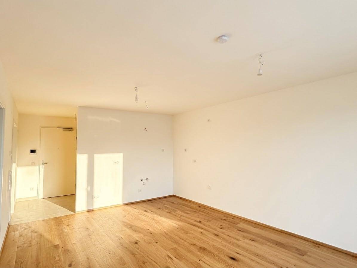 Lichtdurchfluteter Wohnbereich mit Holzboden und Zugang zum Eingangsbereich.