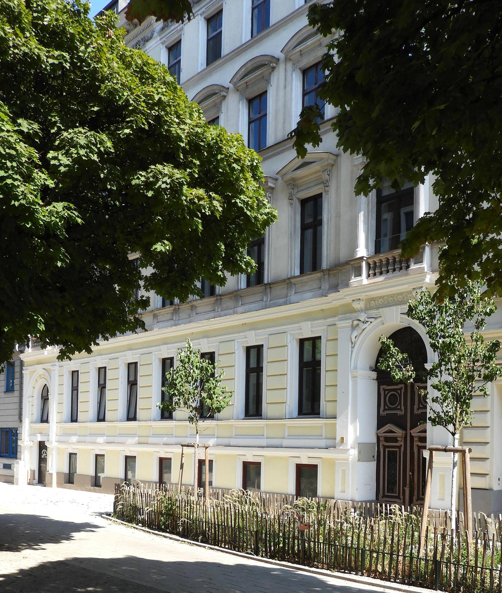 Detailansicht der historischen Fassade mit verzierten Fenstern und einem großen Eingangstor.