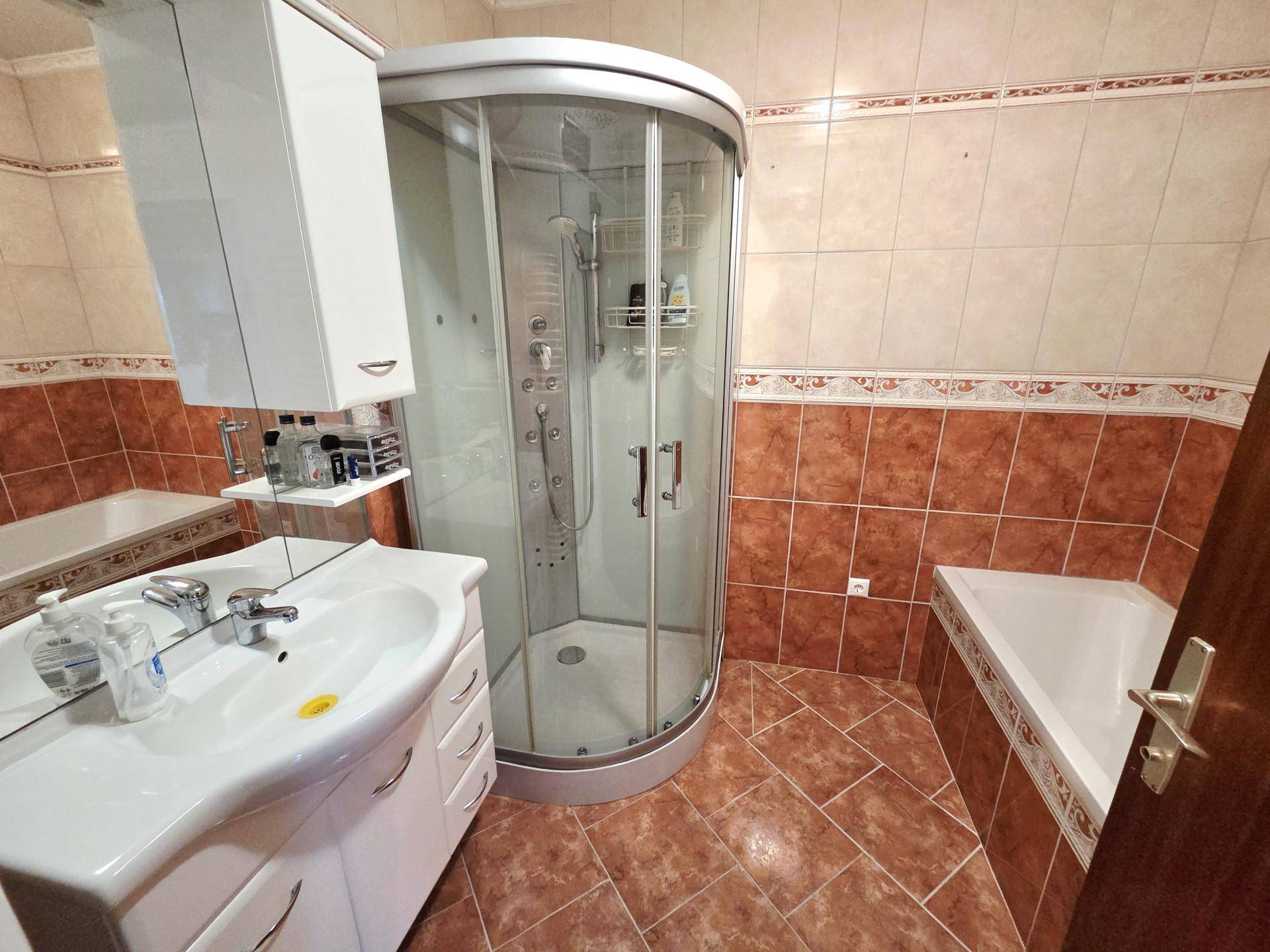 Badezimmer mit Duschkabine, Einzelwaschbecken und Eckbadewanne in traditionellem Stil.