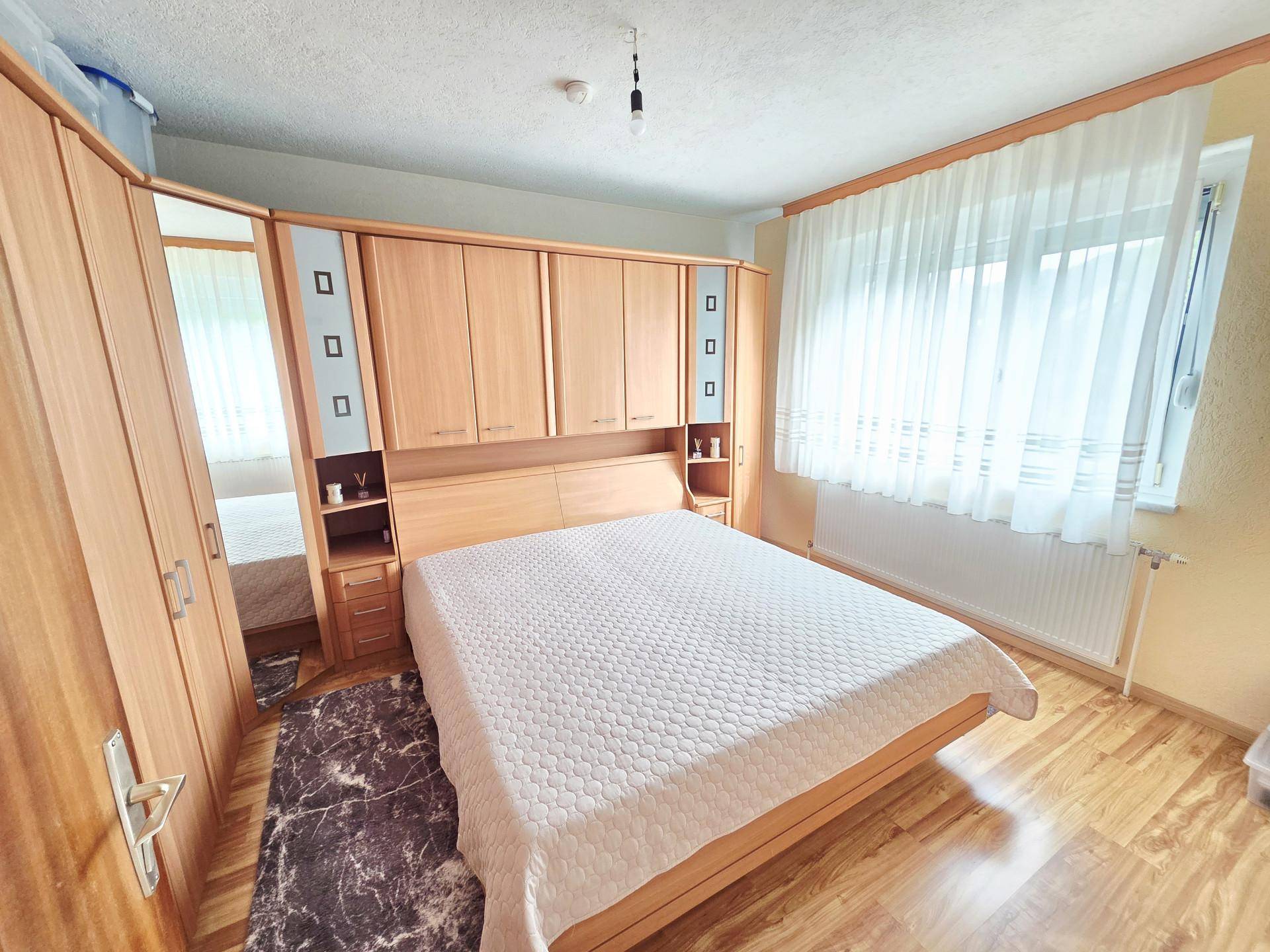 Schlafzimmer mit integrierten Holzschränken, Doppelbett und Laminatboden.
