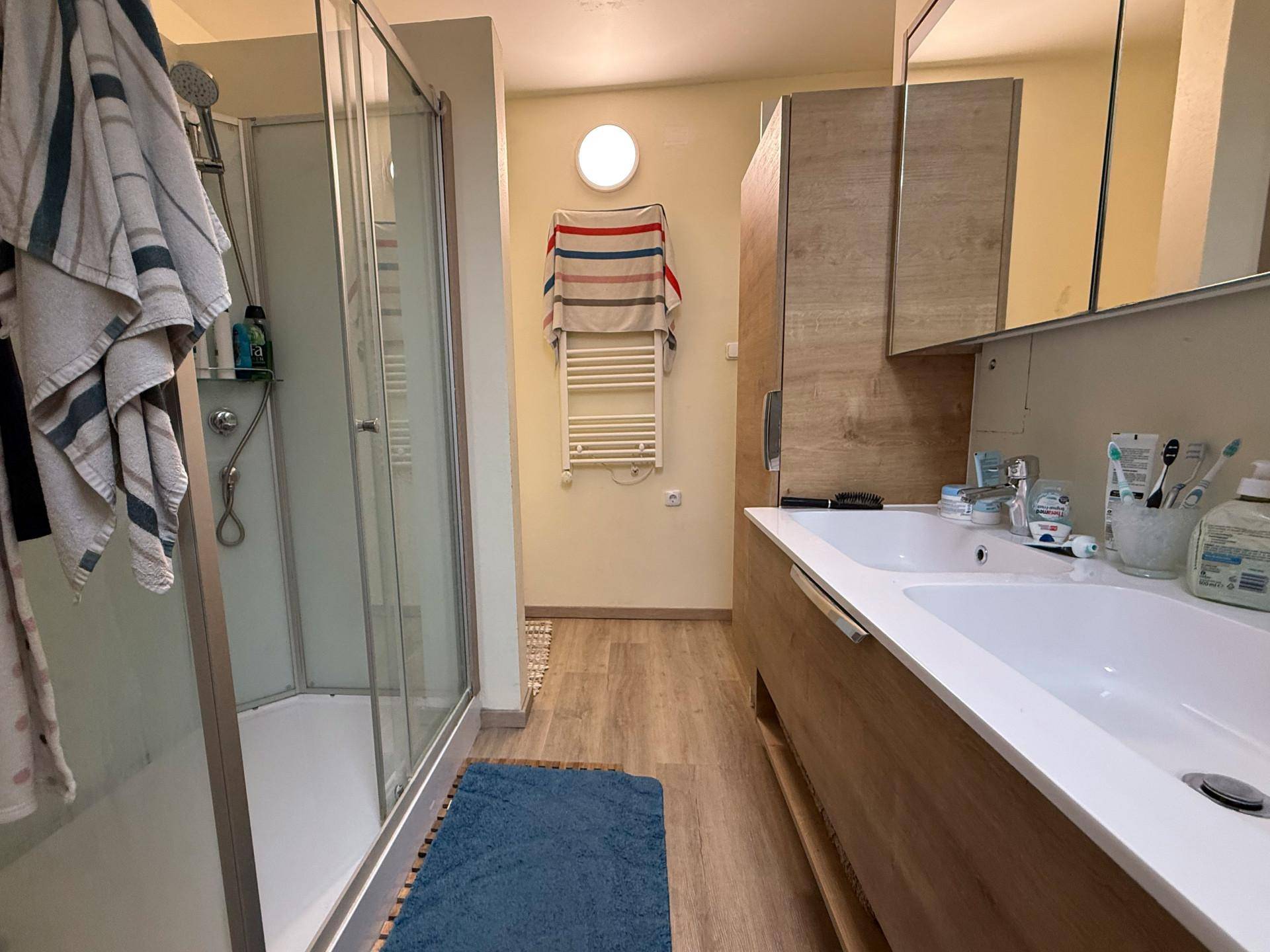 Modernes Badezimmer mit Doppelwaschbecken, Duschkabine und Handtuchheizkörper.