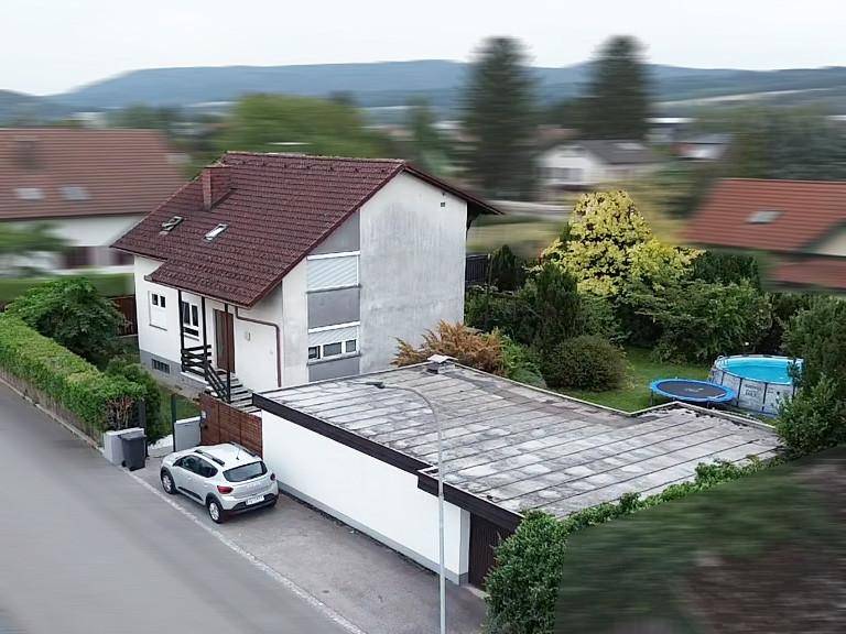 Übersicht des Einfamilienhauses von oben mit angrenzender Garage und Gartenbereich.