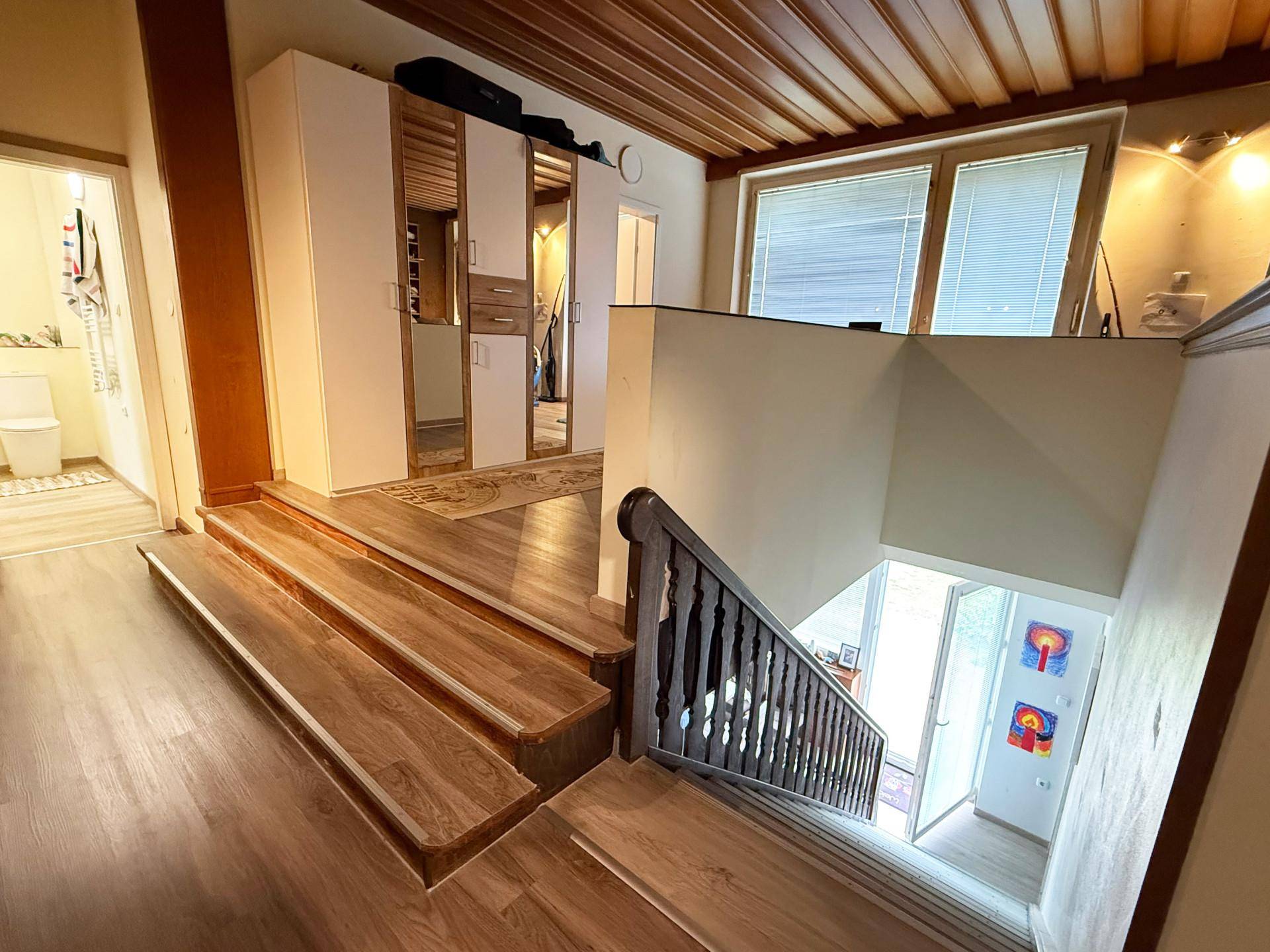 Geräumiger Flur mit Holzdecke, Laminatboden und Treppe zum unteren Bereich.