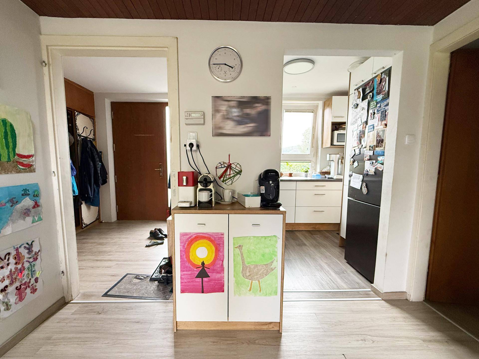 Flur mit Zugang zur Küche und einem weiteren Raum, dekoriert mit Kinderzeichnungen.