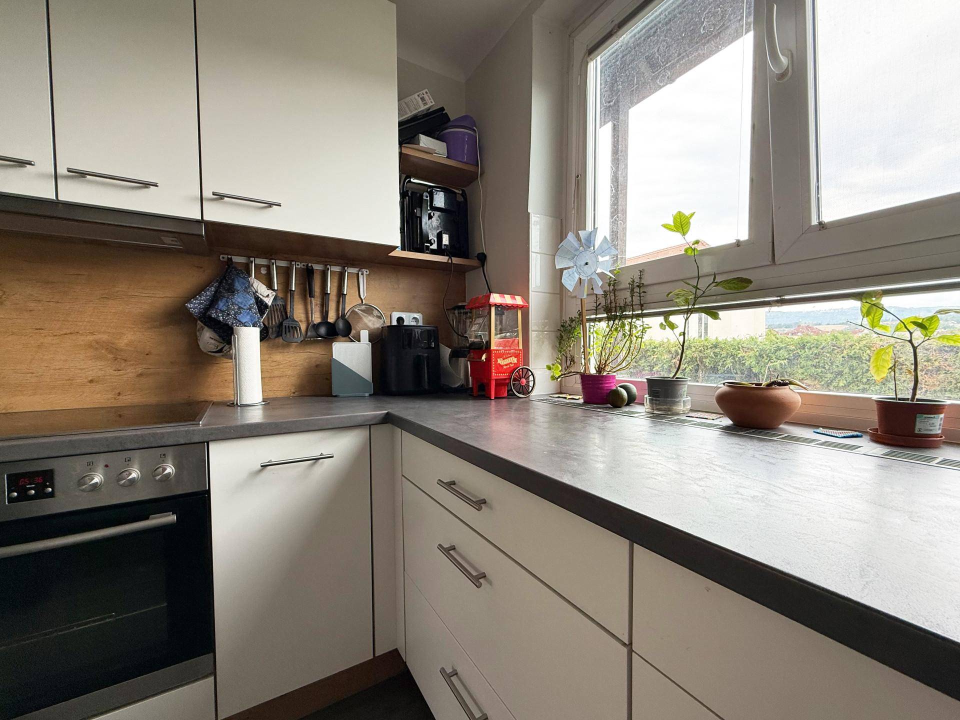 Helle Küche mit Arbeitsplatte, Fenster und Blick auf die Umgebung.