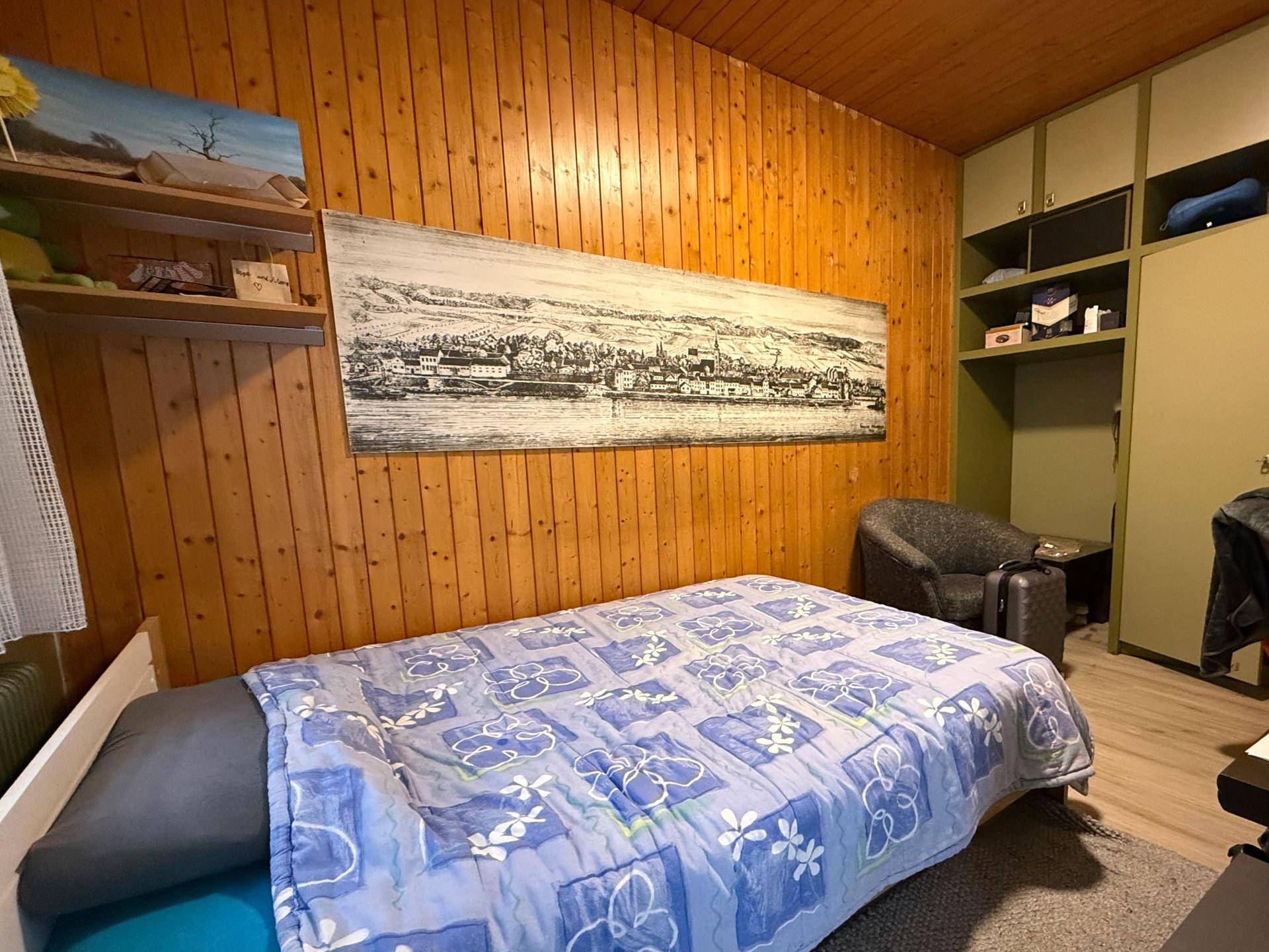 Schlafzimmer mit Holzvertäfelung, Einzelbett und Einbauschränken.