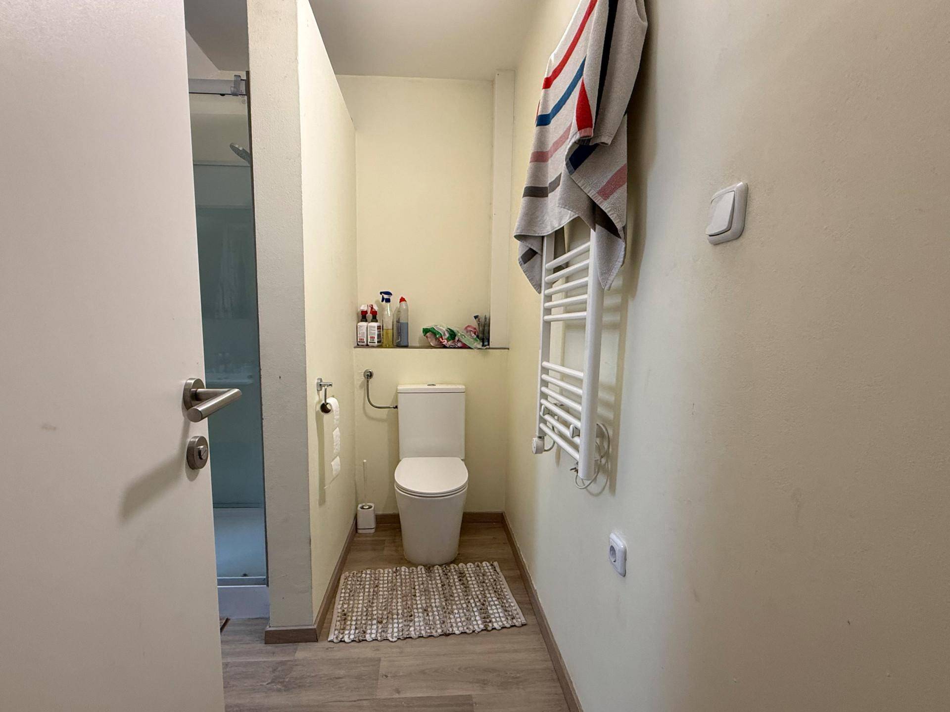 Kleines Badezimmer mit Toilette, Duschkabine und beheiztem Handtuchhalter.