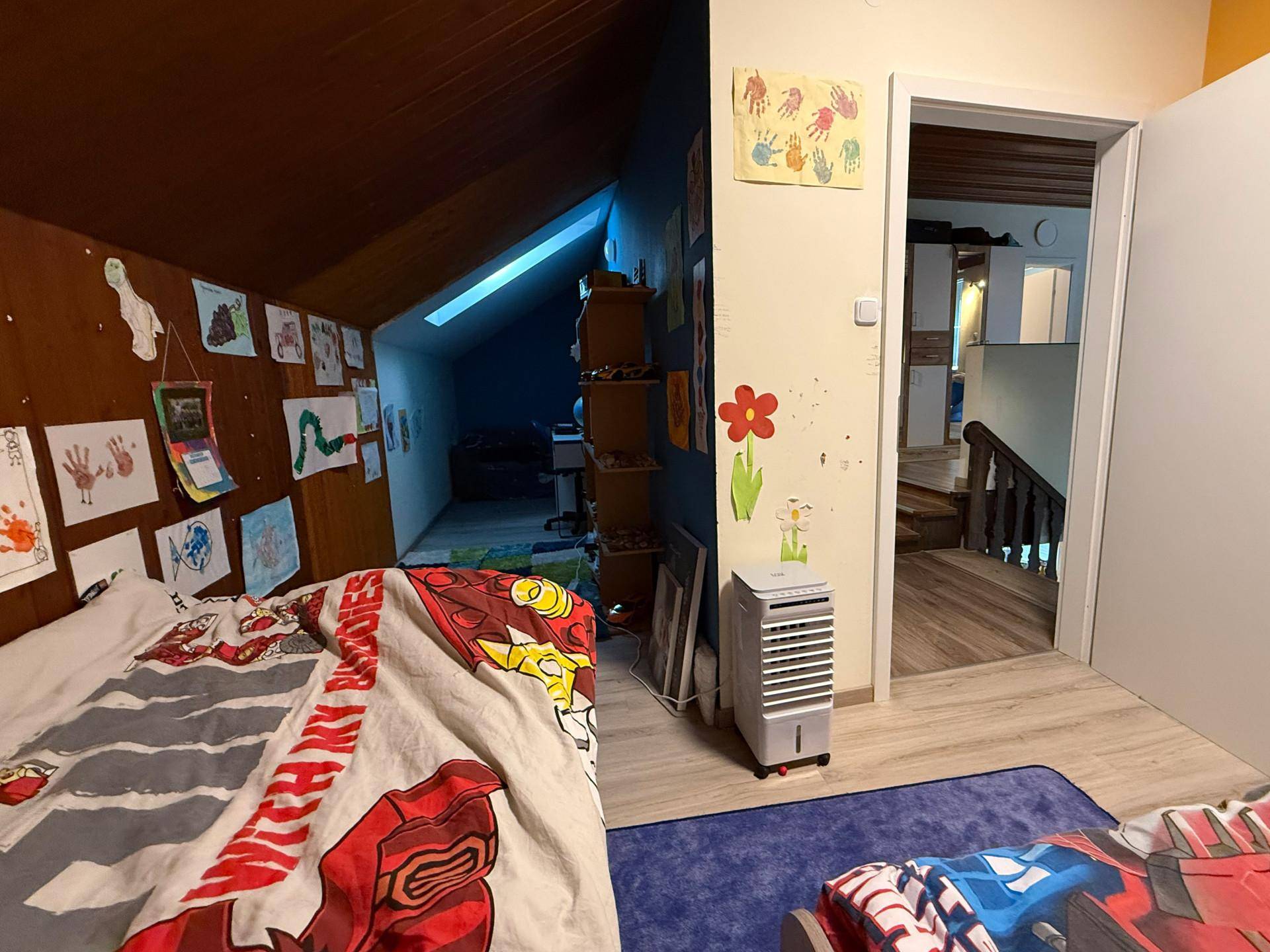 Kinderzimmer im Dachgeschoss mit schrägen Wänden, bunten Dekorationen und einem Bett.