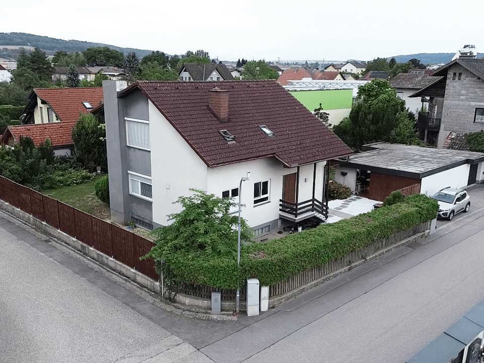 Freistehendes Einfamilienhaus mit Satteldach, gepflegtem Garten und Hecke in ruhiger Wohngegend.