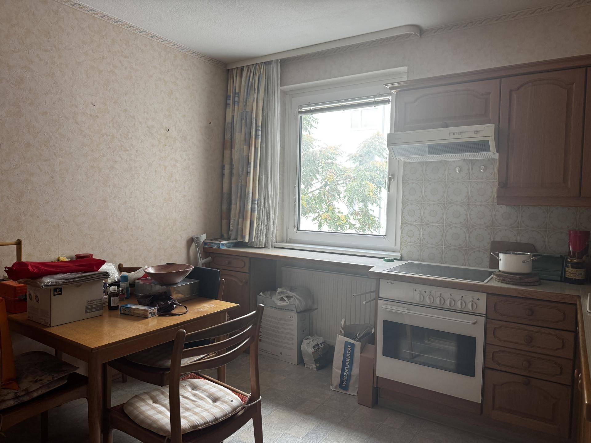 Küche mit Essbereich, Fenster und Einbauküche, die aufgeräumt werden muss.