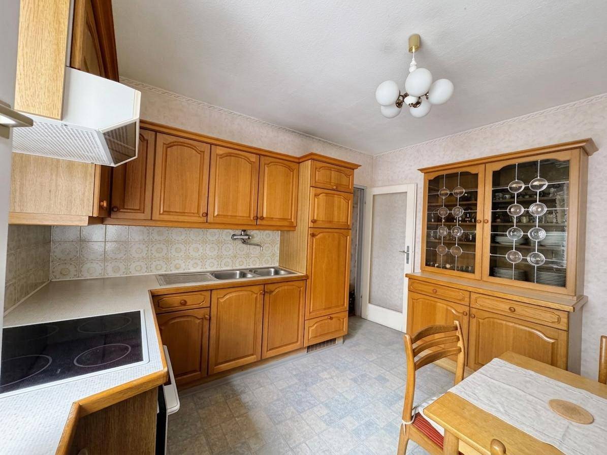 Traditionelle Holzküche mit Einbauschränken, Spülbecken und einem dekorativen Vitrinenschrank.