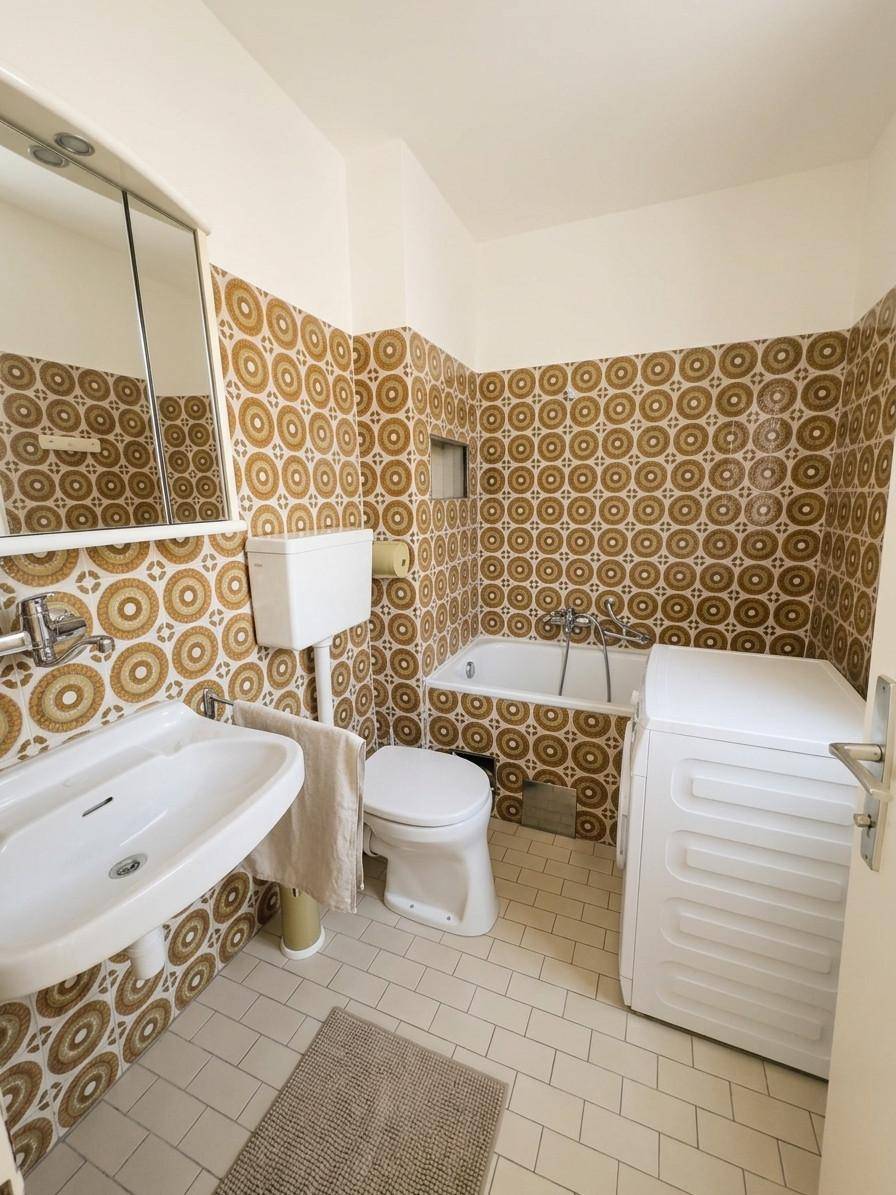 Badezimmer mit auffälligen braun-weißen Fliesen, Badewanne, Waschbecken und Toilette.