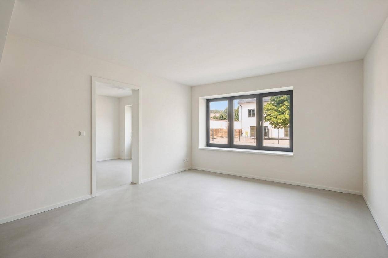 Heller Innenraum im Rohbau mit großem Fenster und Blick auf die Umgebung.
