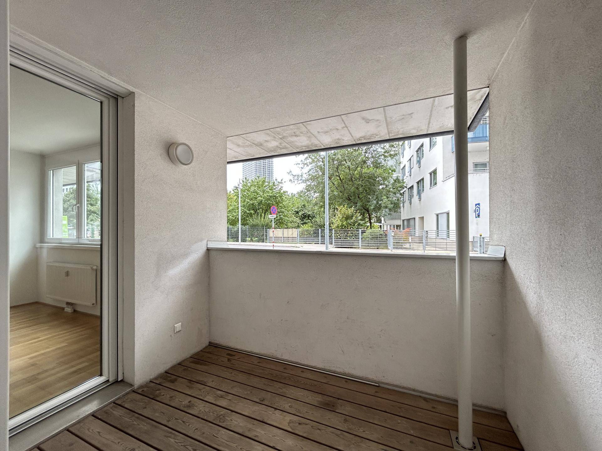 Balkon mit Holzboden und Glasgeländer, bietet einen angenehmen Blick auf die Umgebung.
