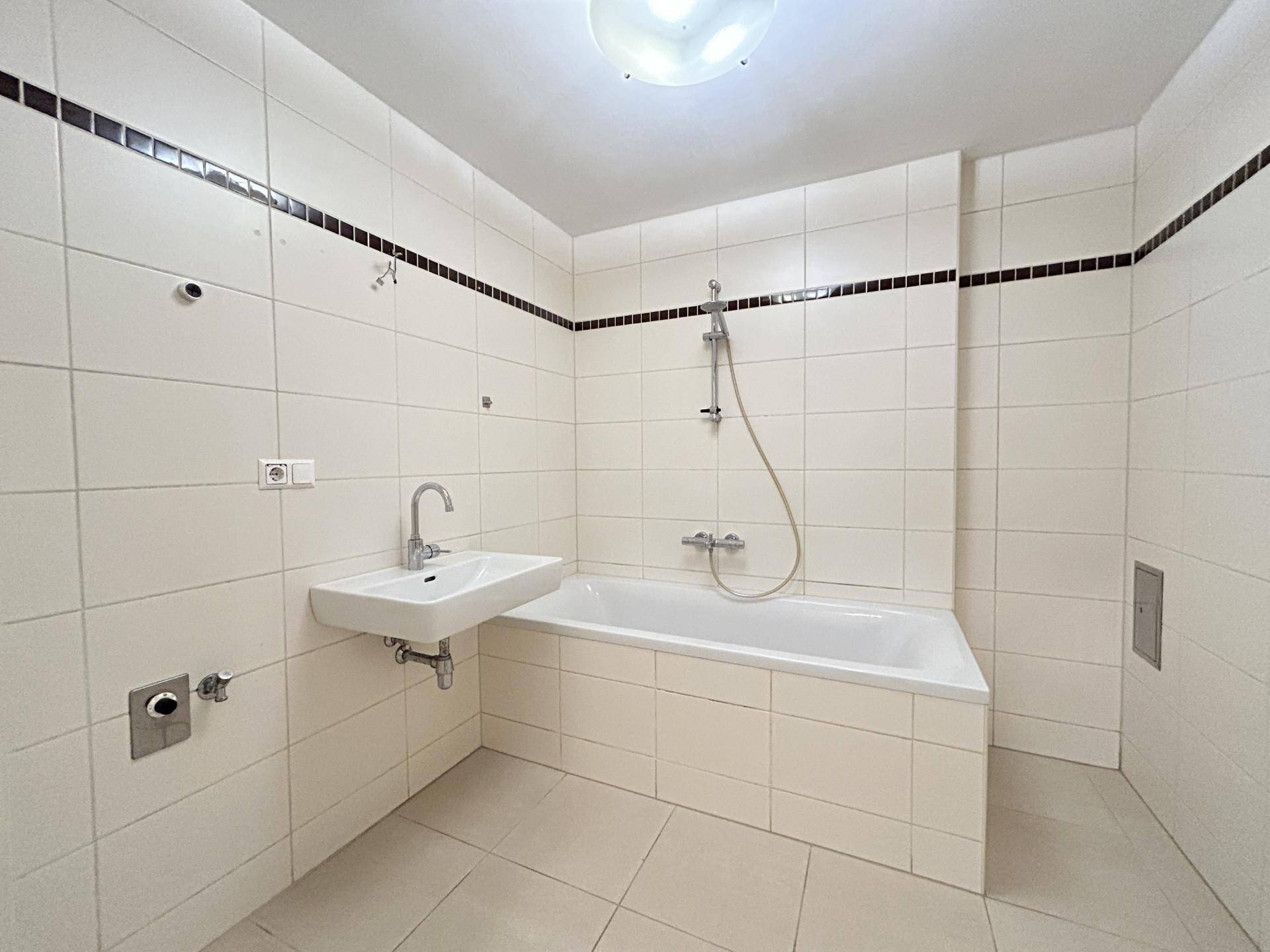 Badezimmer mit weißen Fliesen, Badewanne und Waschbecken, funktional und sauber gestaltet.
