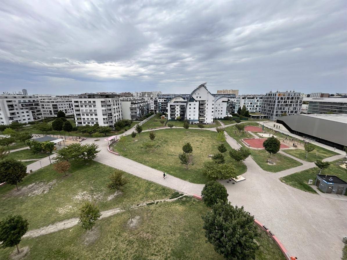 Weitläufige Grünfläche mit Spielplätzen, umgeben von modernen Wohngebäuden in der Stadt.