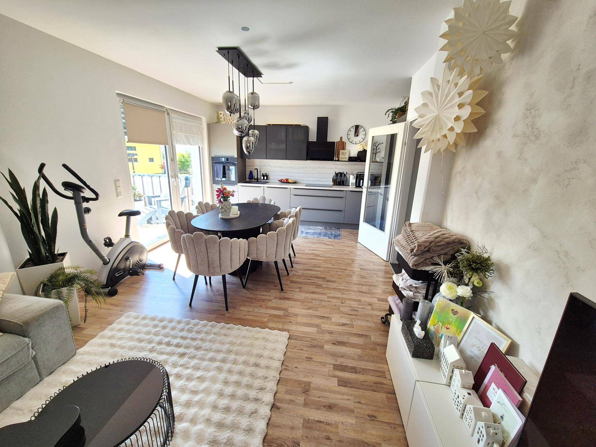 Offener Wohnbereich mit Essplatz, moderner Küche und Zugang zum Balkon.