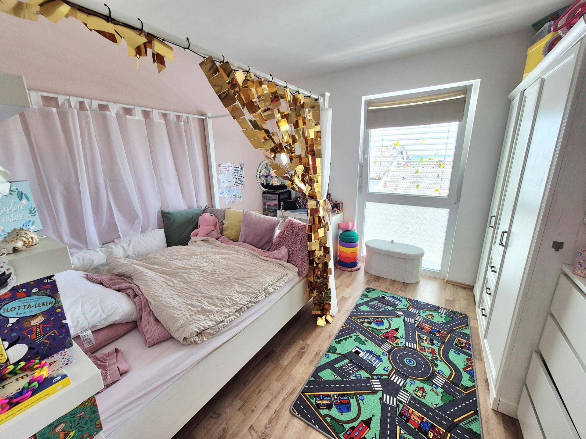 Kinderzimmer mit verspielter Dekoration, Einzelbett und großem Fenster.