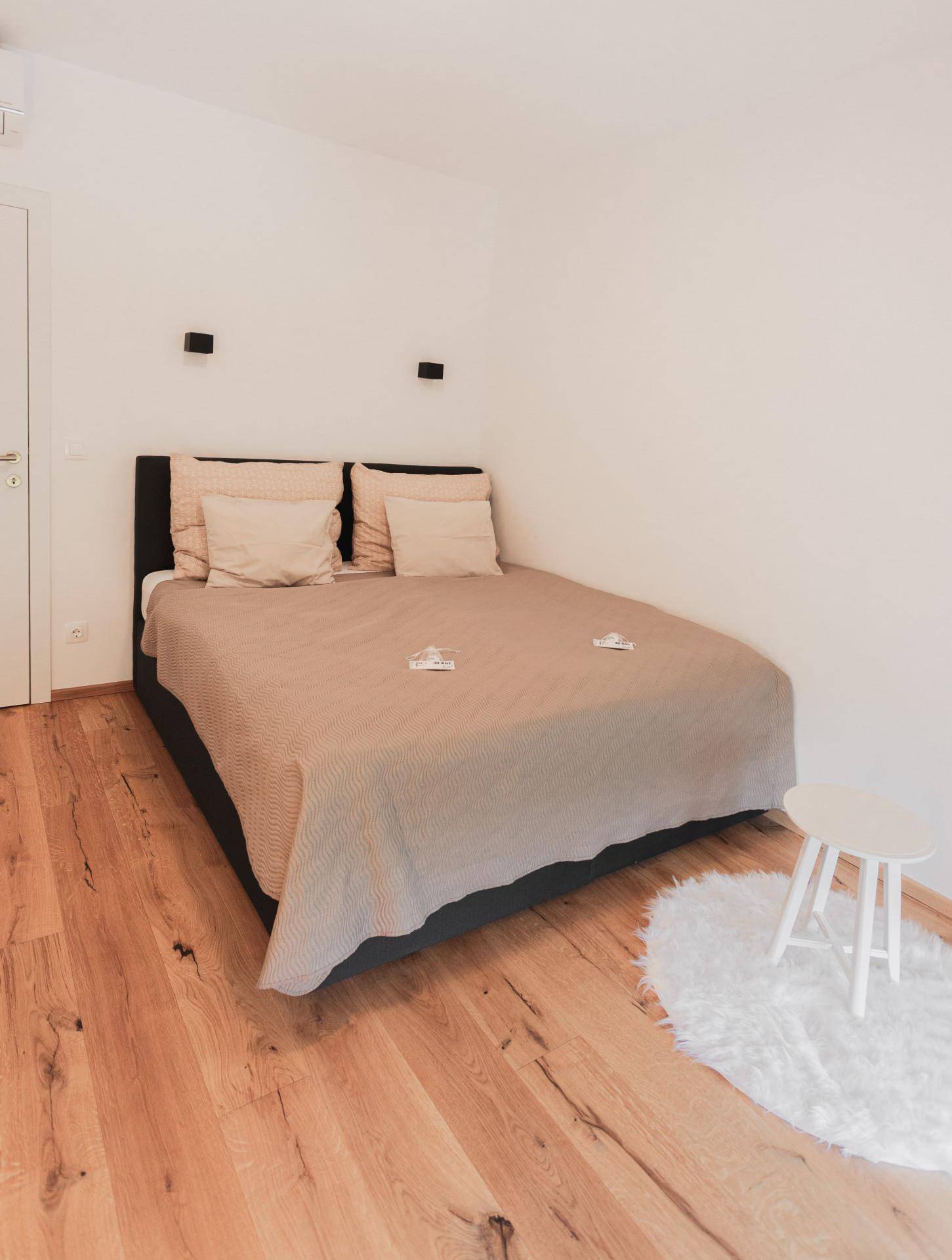 Gemütliches Schlafzimmer mit Doppelbett, Holzboden und minimalistischer Einrichtung für erholsame Nächte.