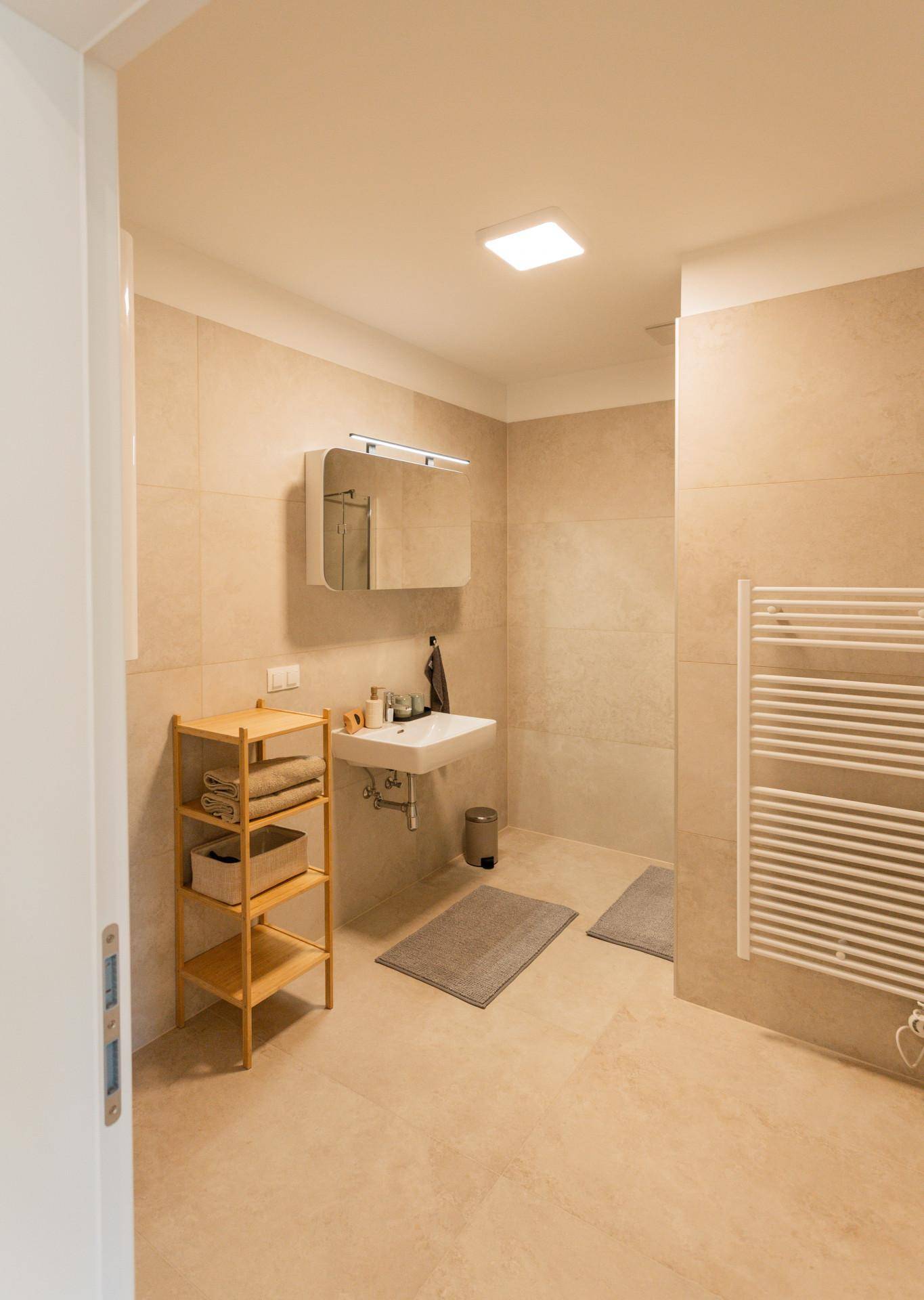 Modernes Badezimmer mit beigen Fliesen, Einzelwaschbecken und beheiztem Handtuchhalter.