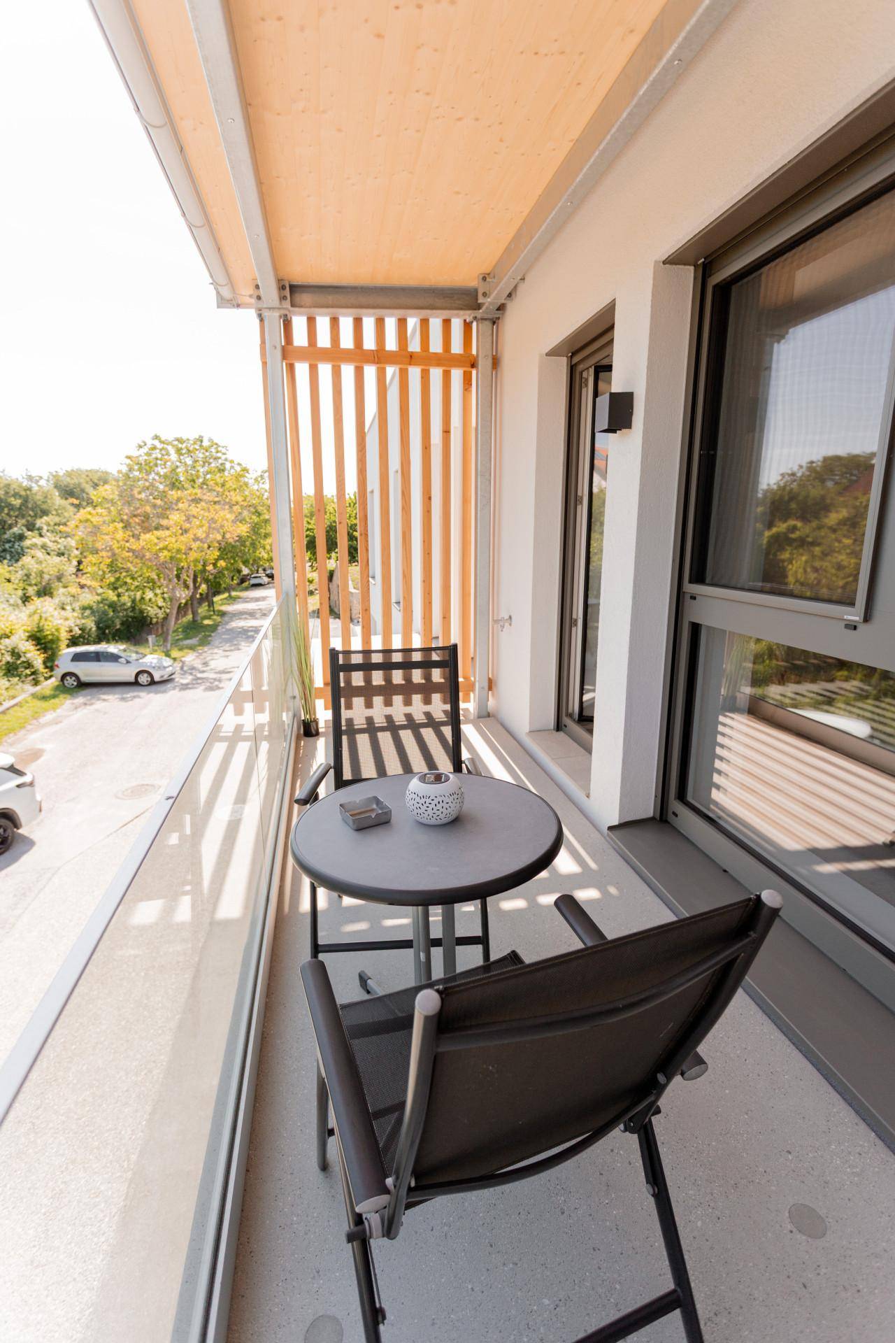 Kleiner Balkon mit Sitzgelegenheiten und Blick auf die Straße, ideal für entspannte Momente.