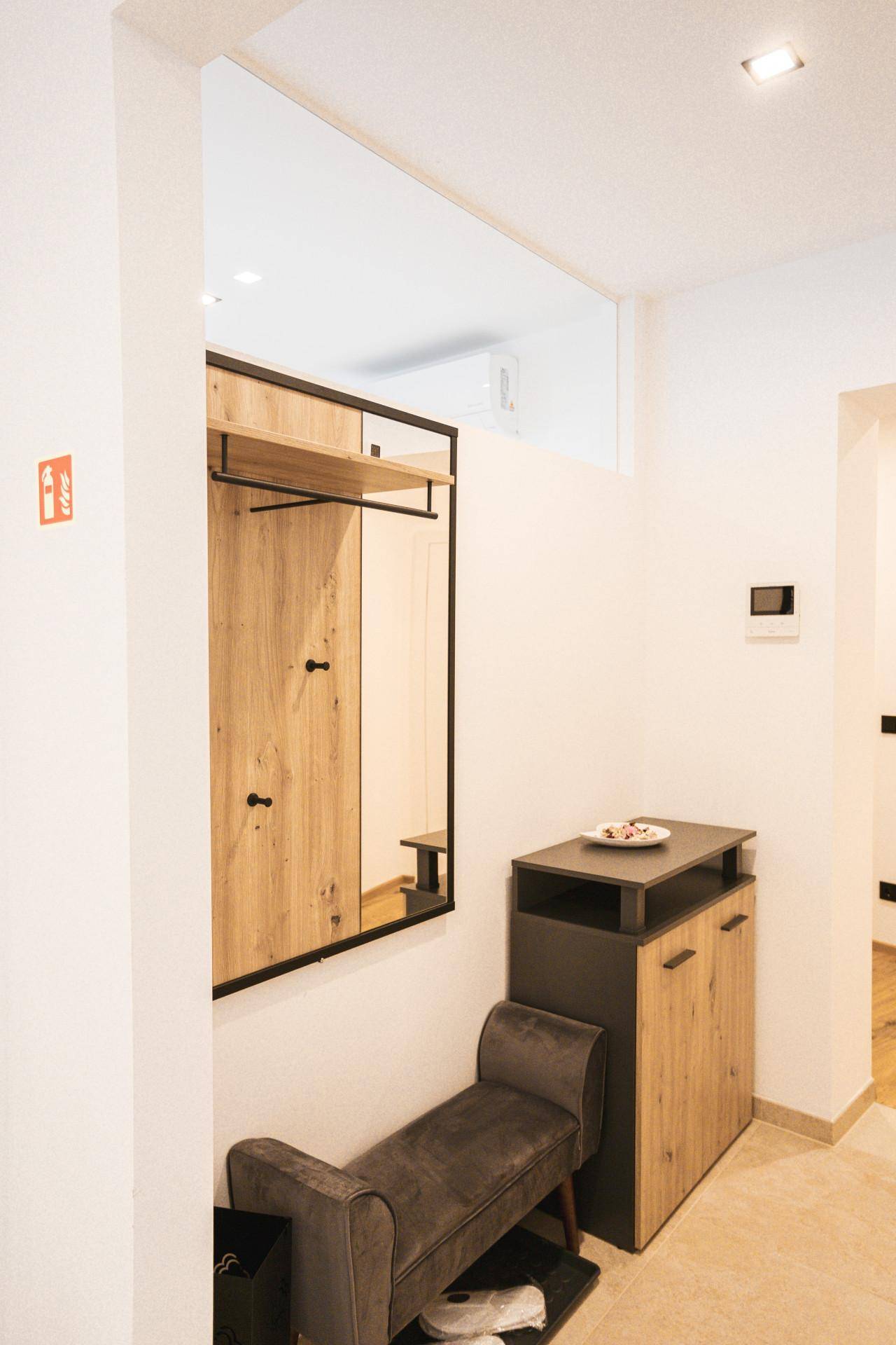 Eingangsbereich mit Garderobe, Spiegel und praktischen Holzmöbeln.