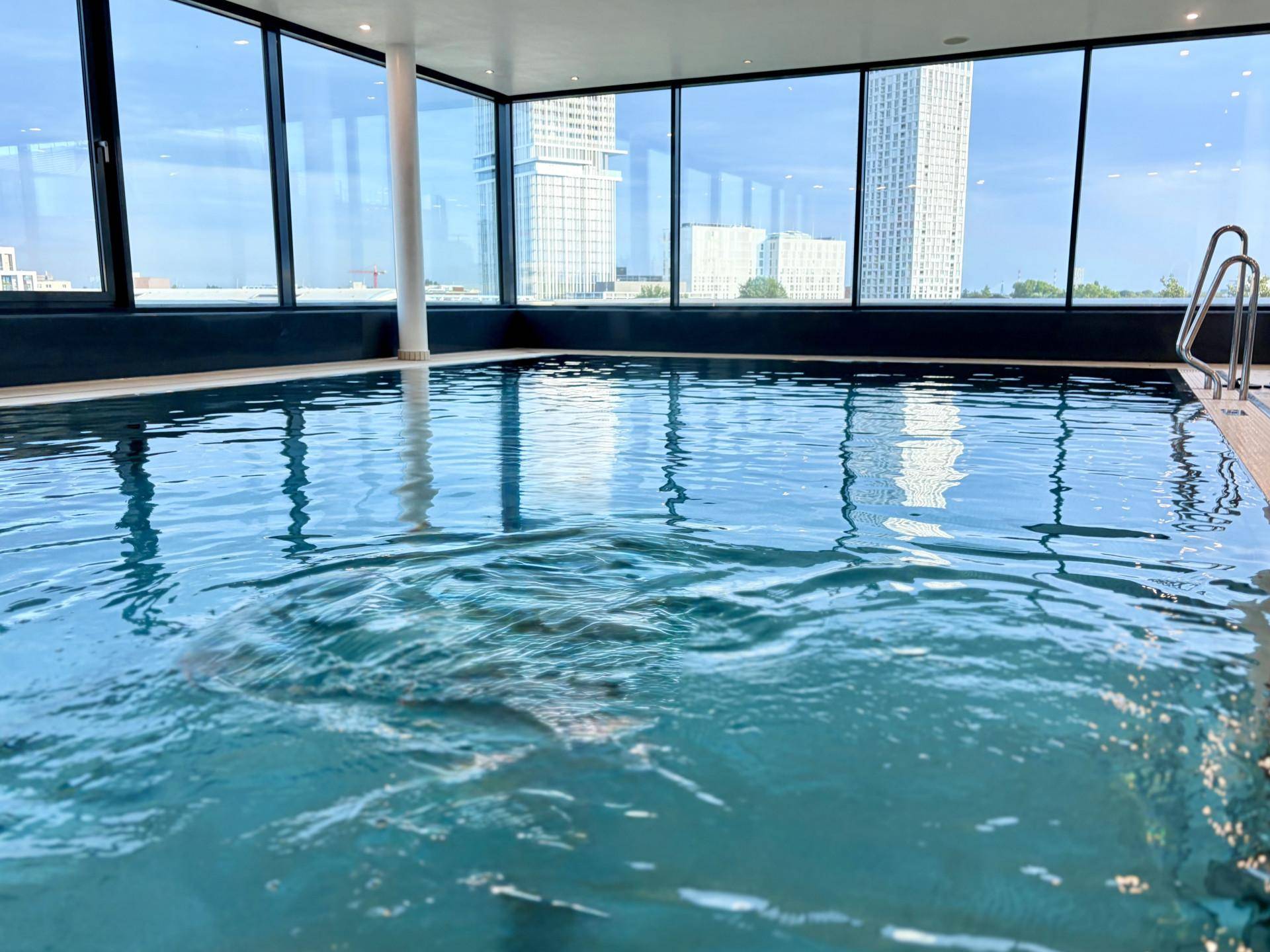 Heller Innenpool mit raumhohen Fenstern, die einen beeindruckenden Blick auf die Stadt bieten.