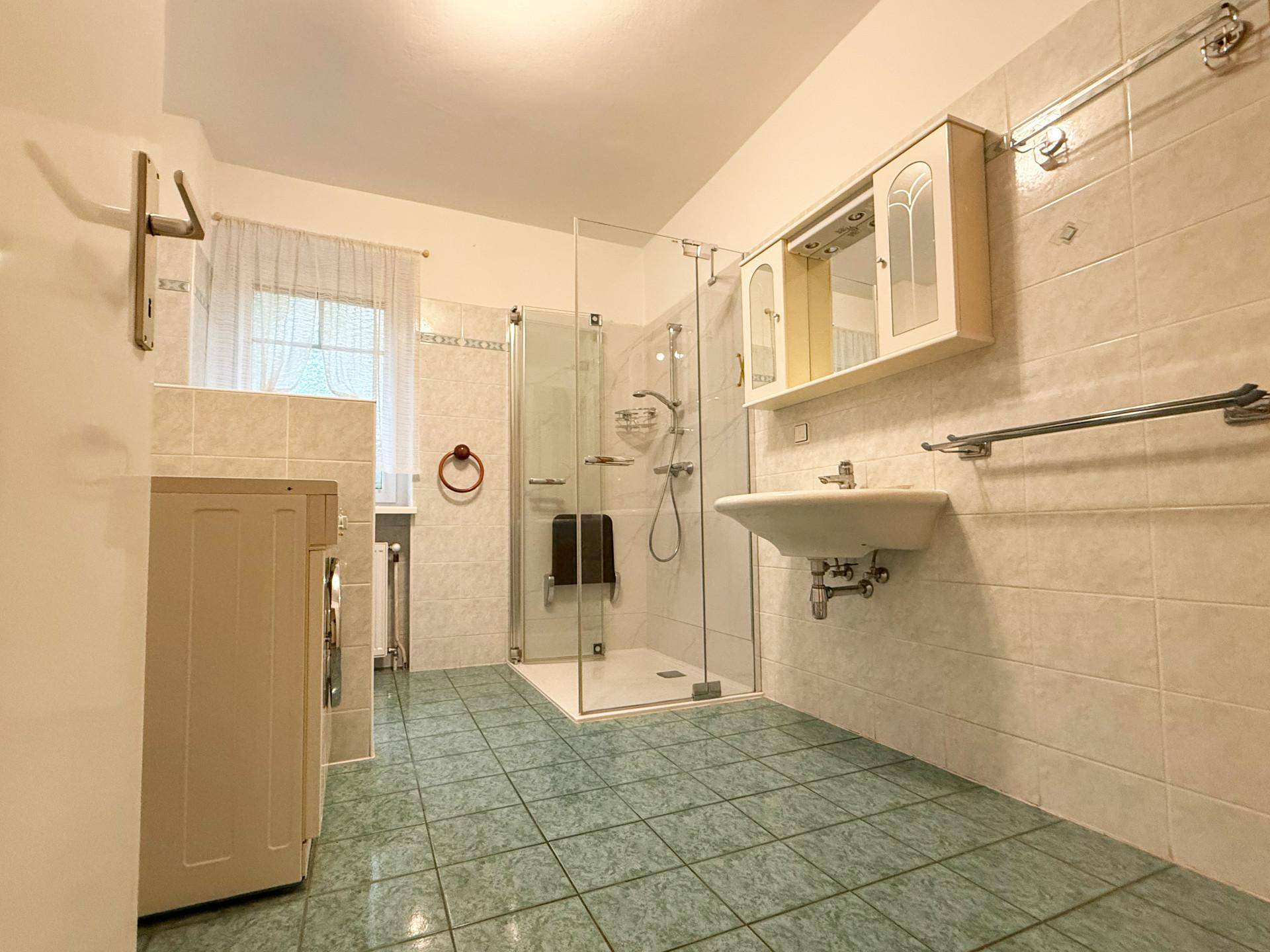 Funktionales Badezimmer mit Duschkabine, Waschbecken und hellen Fliesen.