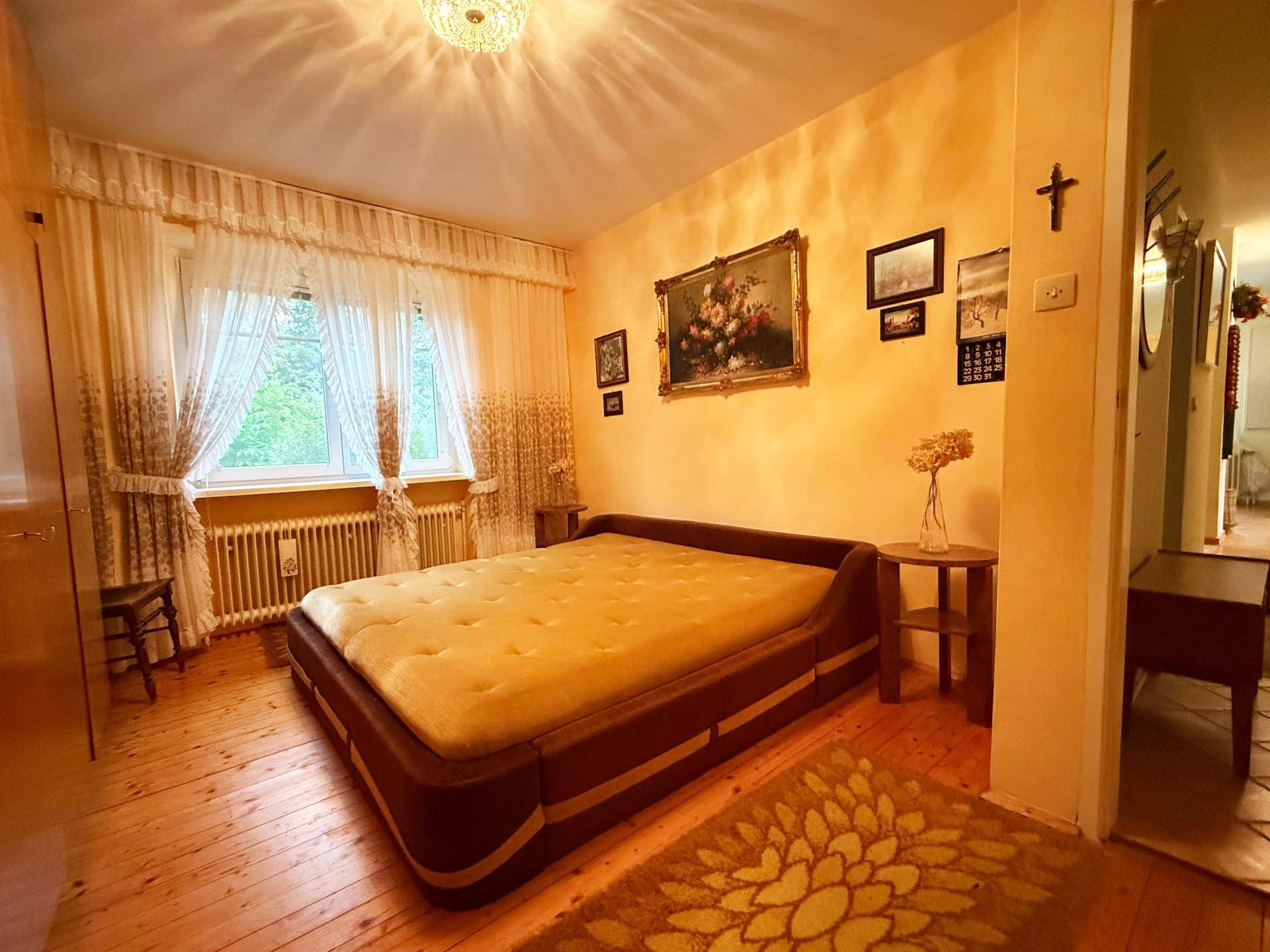 Gemütliches Schlafzimmer mit Doppelbett, Holzboden und traditioneller Dekoration.