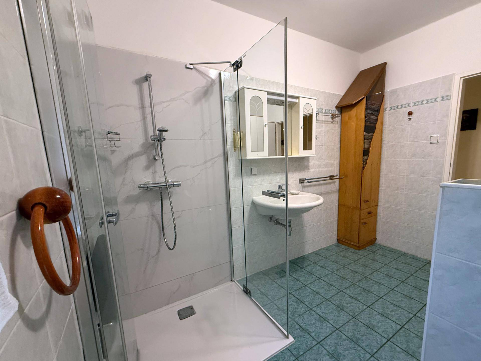 Helles Badezimmer mit Duschkabine, Waschbecken und Spiegelschrank.