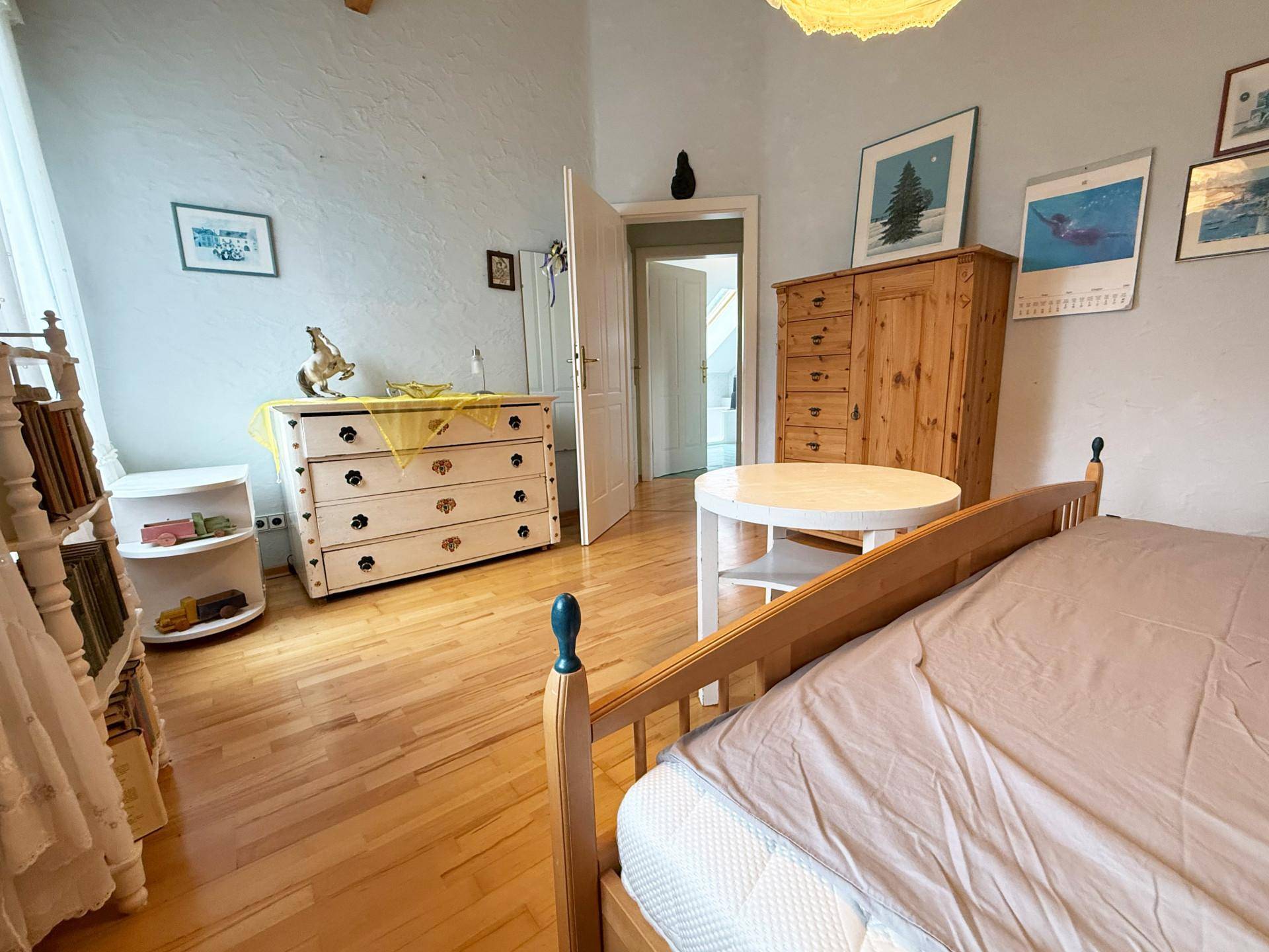 Geräumiges Schlafzimmer mit Holzboden, traditionellen Möbeln und Blick auf den Garten.