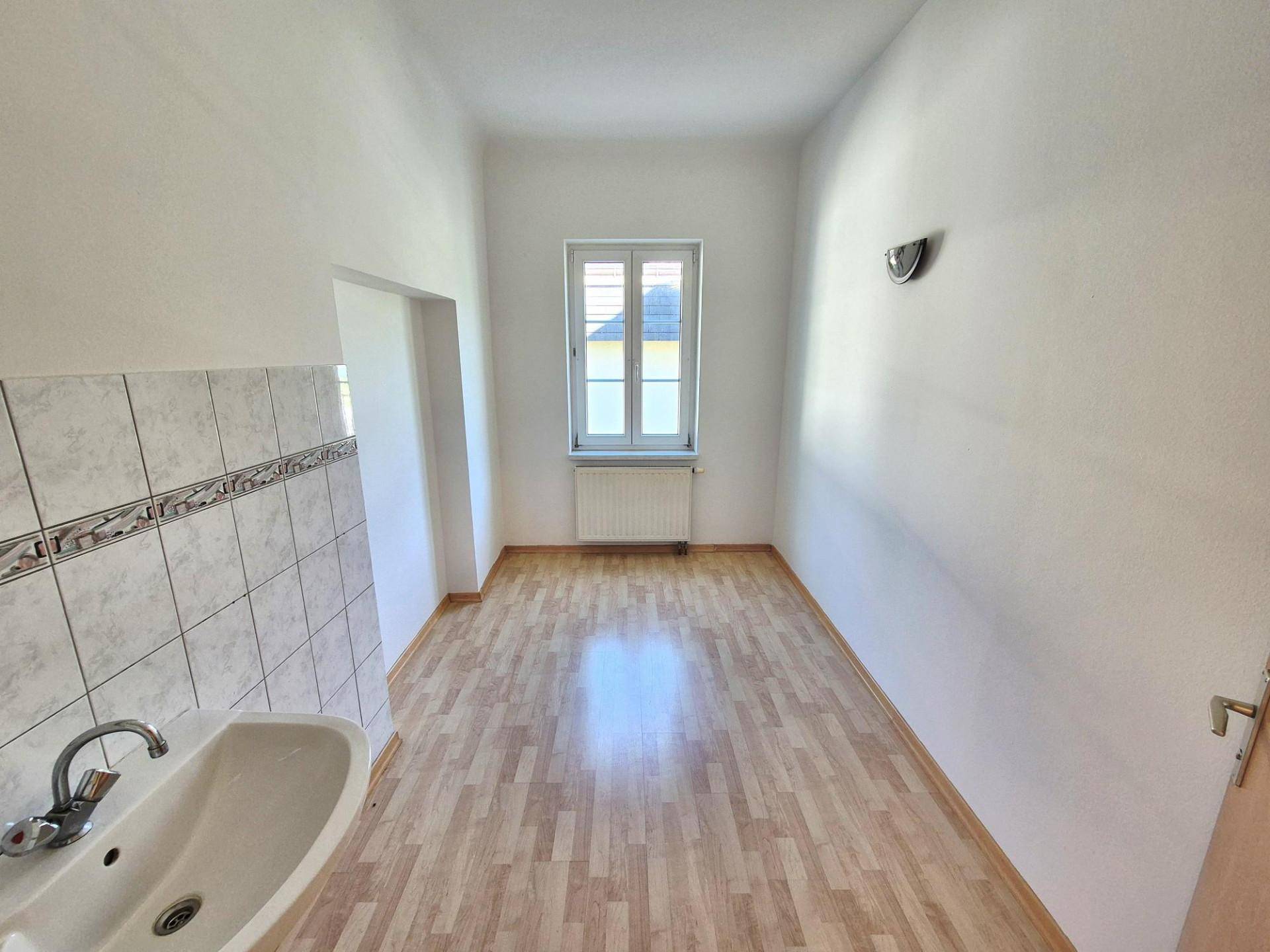 Funktionaler Raum mit Laminatboden, Waschbecken und Fenster, geeignet als Hauswirtschaftsraum.