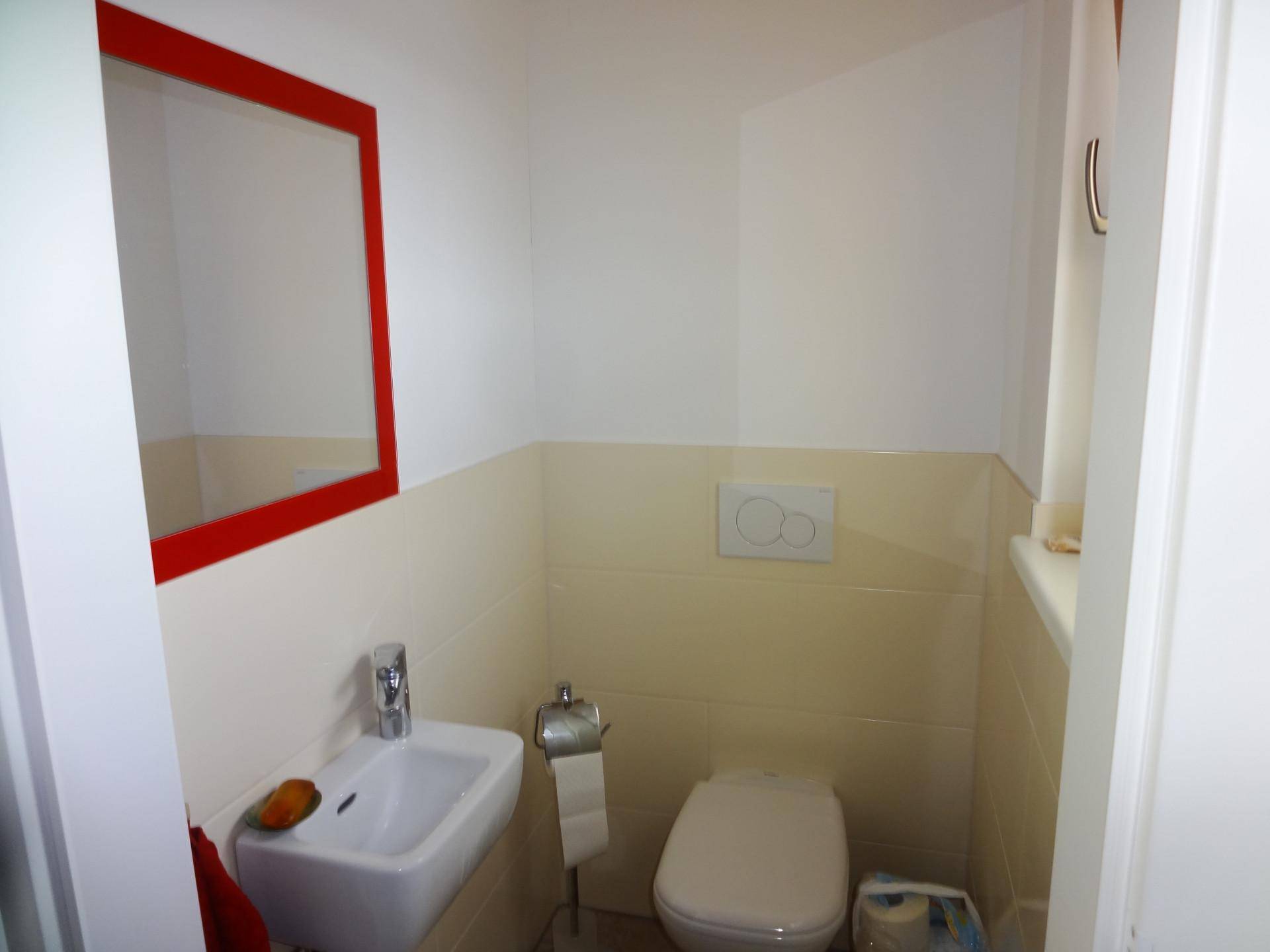 Kleines Gäste-WC mit Toilette, Waschbecken und Spiegel in schlichtem Design.