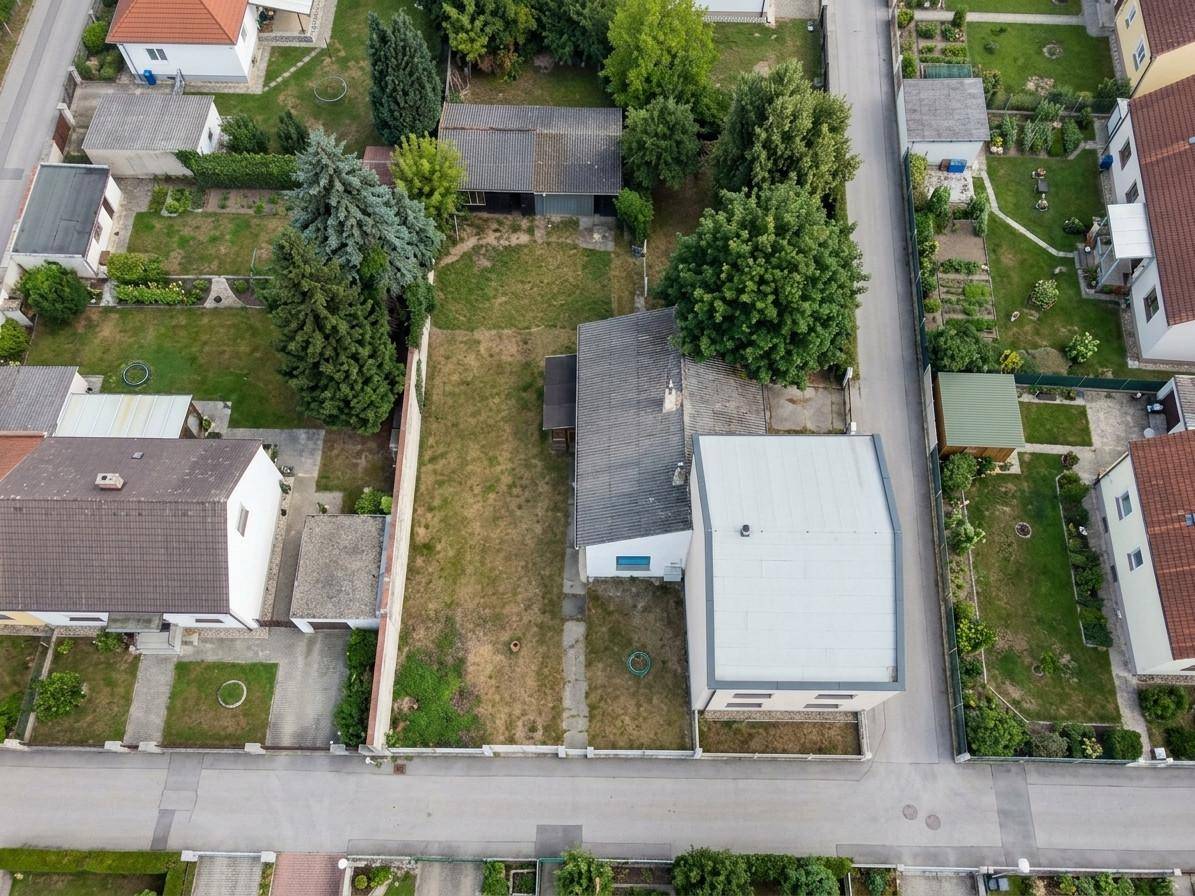 Luftaufnahme eines Grundstücks mit Haus, langem Garten und umliegender Wohnbebauung in ländlicher Umgebung.