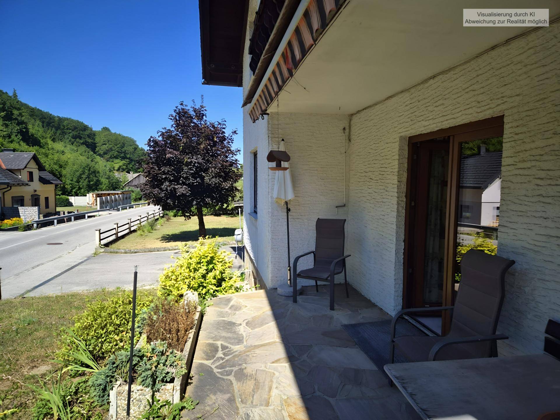 Sonniger Terrassenbereich mit Gartenmöbeln und Blick auf die Straße und Umgebung.