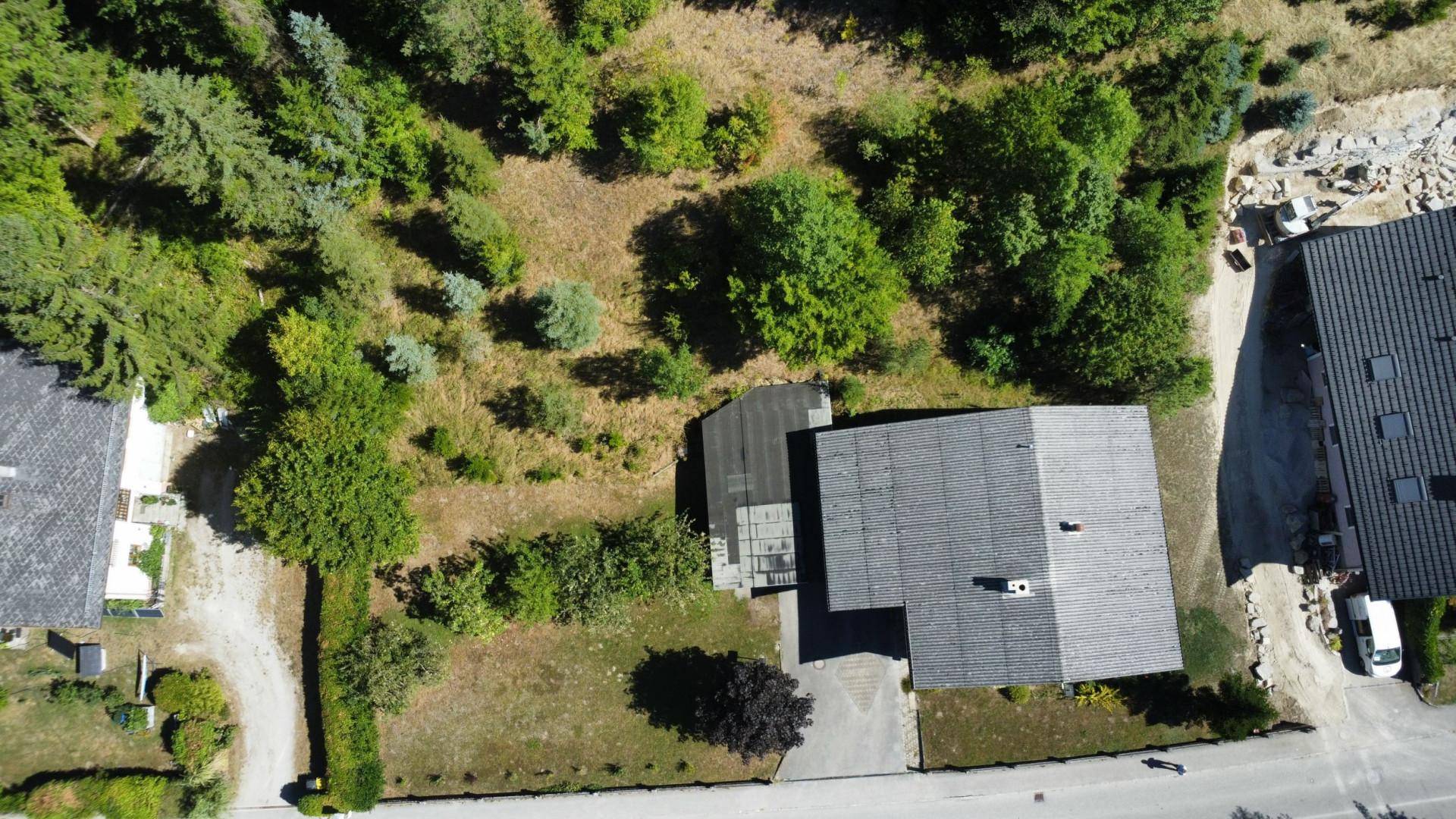 Weitläufige Luftaufnahme des Hauses und des umliegenden bewaldeten Grundstücks mit Nachbarbebauung.