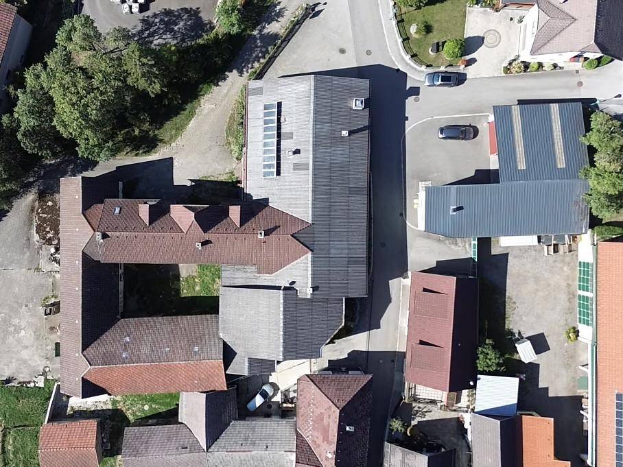 Senkrechte Luftaufnahme des Gebäudekomplexes mit Dächern, Parkplätzen und umliegenden Straßen.