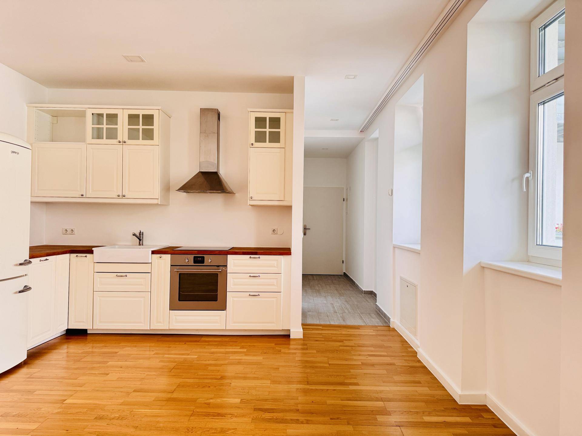 Funktionale Einbauküche in Weiß mit Holz-Arbeitsplatte und modernen Geräten in einem offenen Wohnbereich.
