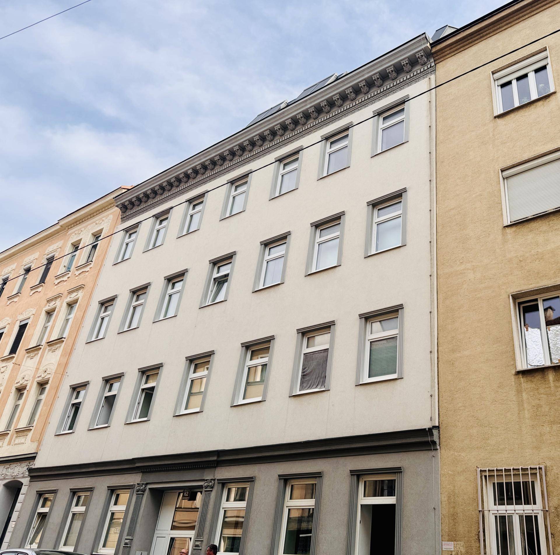 Klassische Gebäudefassade mit mehreren Stockwerken und Fenstern an einer städtischen Straße.