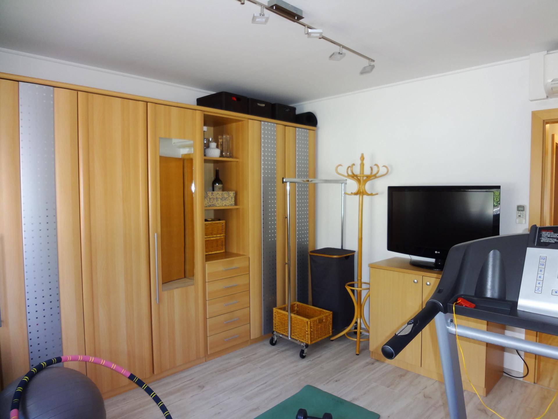 Vielseitiger Raum mit Einbauschränken, Fernseher und Fitnessgeräten.