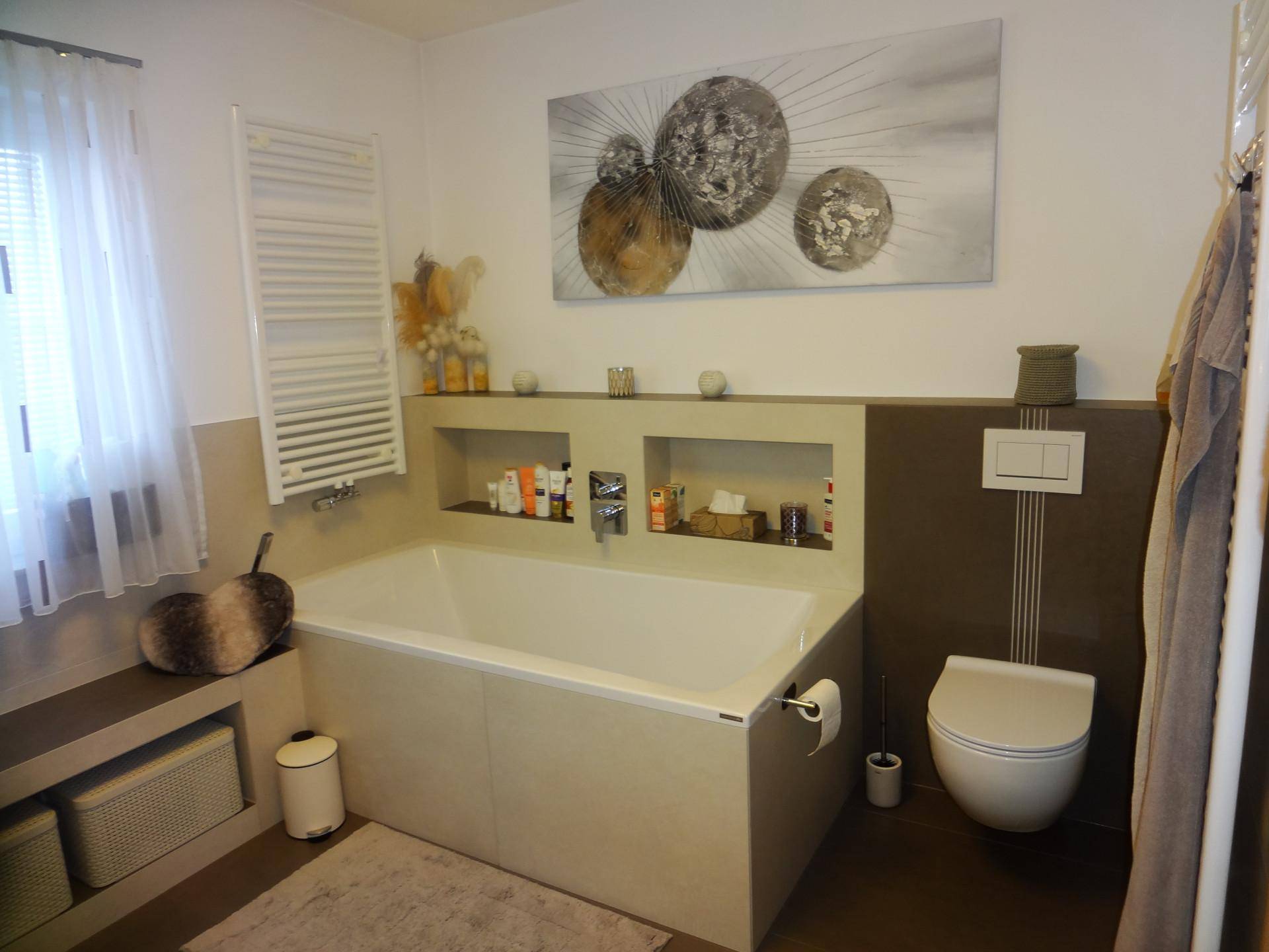 Modernes Badezimmer mit Badewanne, Wand-WC und beheiztem Handtuchhalter.