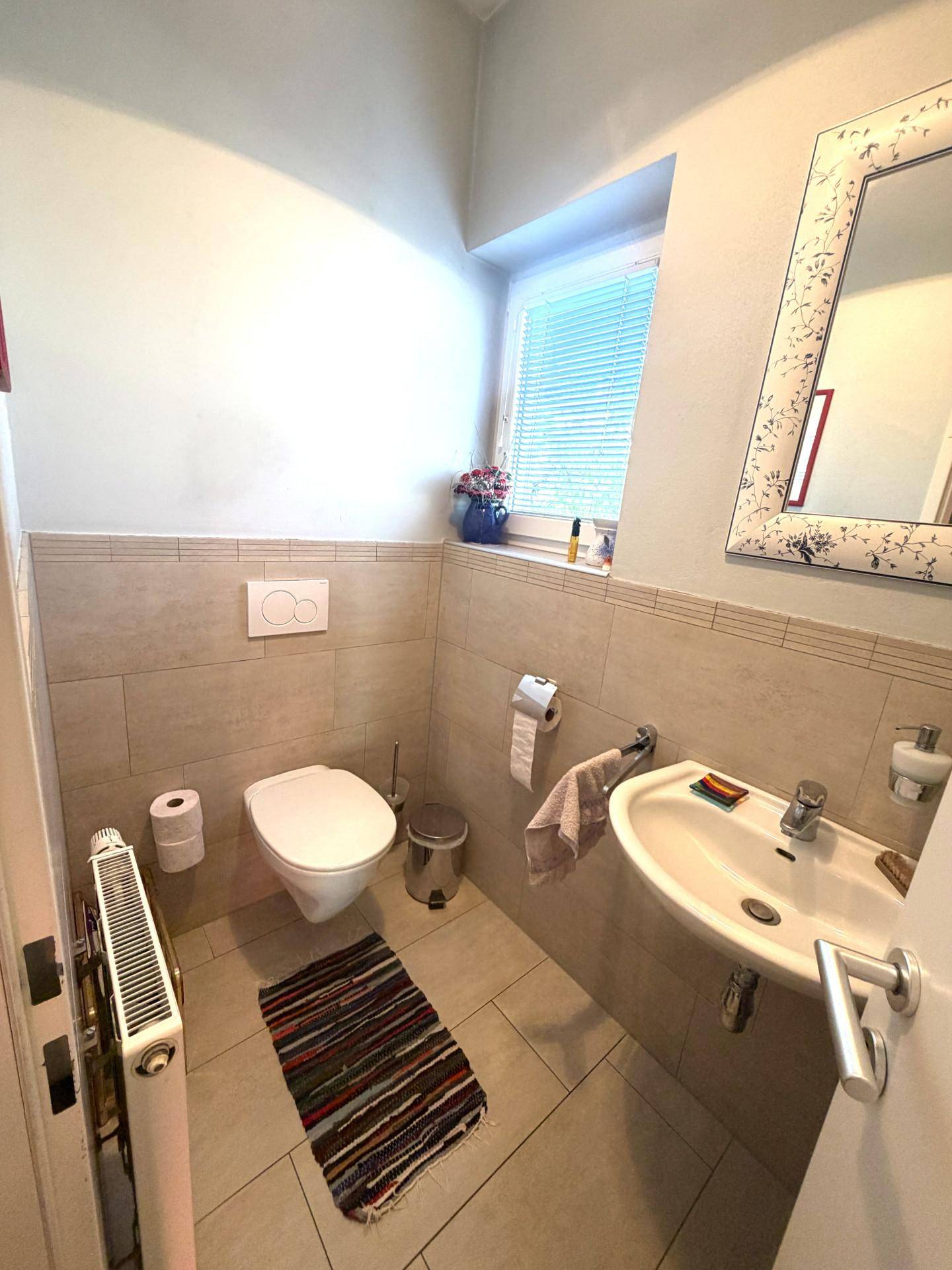Kleines Gäste-WC mit Wand-WC, Waschbecken und Fenster.