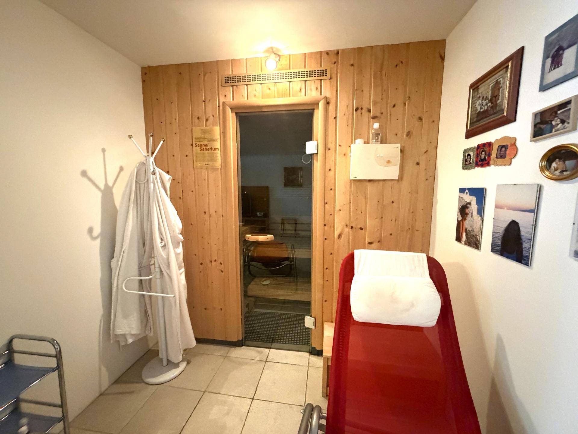 Entspannungsbereich mit Zugang zur Sauna, ausgestattet mit Liege und Holzverkleidung.