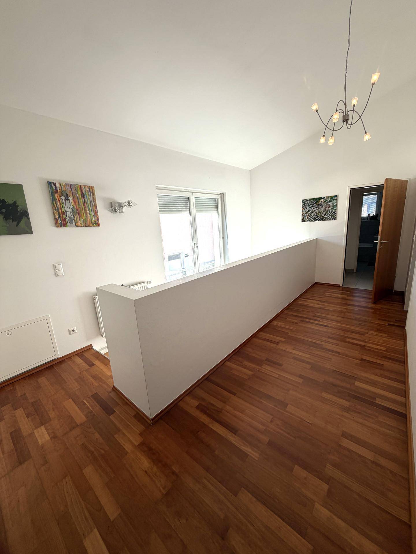 Heller Flur im Obergeschoss mit Holzboden und Blick auf den Treppenbereich.