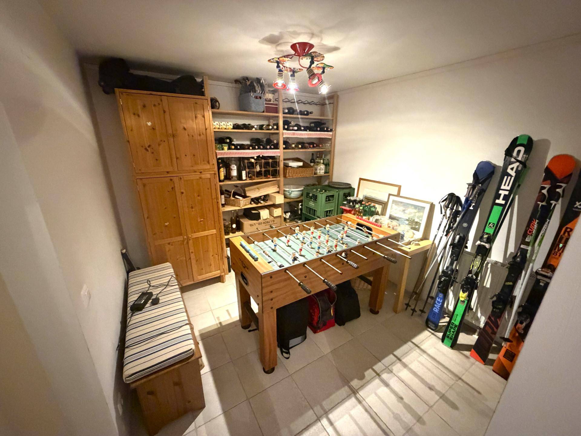 Vielseitiger Abstellraum mit Weinregalen, Tischfußball und Stauraum für Sportgeräte.