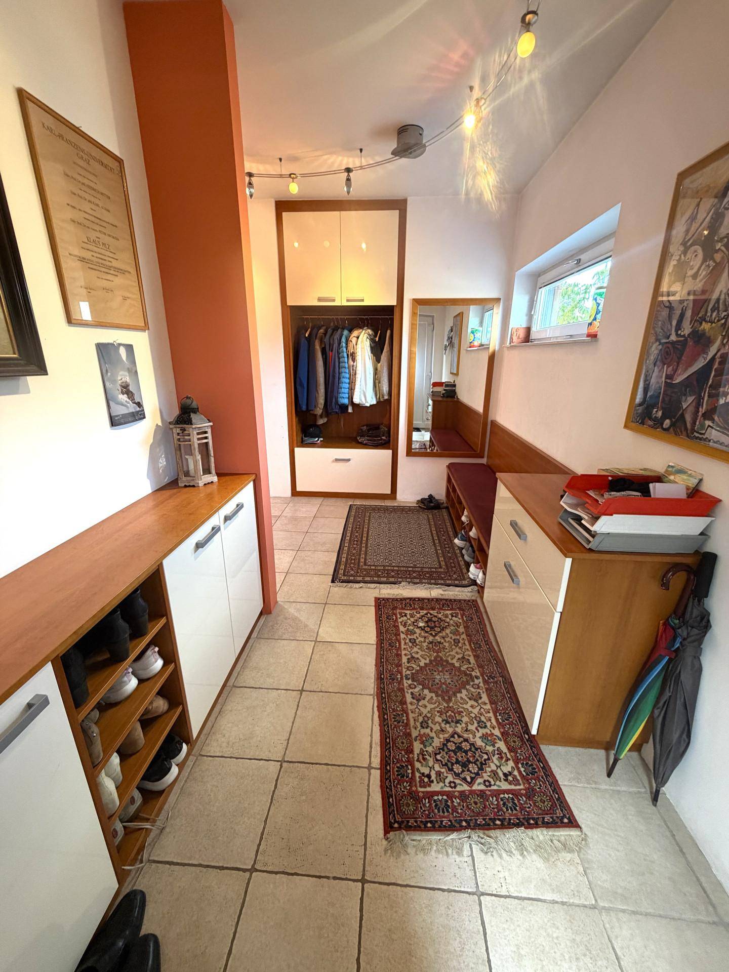 Heller Eingangsbereich mit Fliesenboden, Garderobe und Schuhschränken.