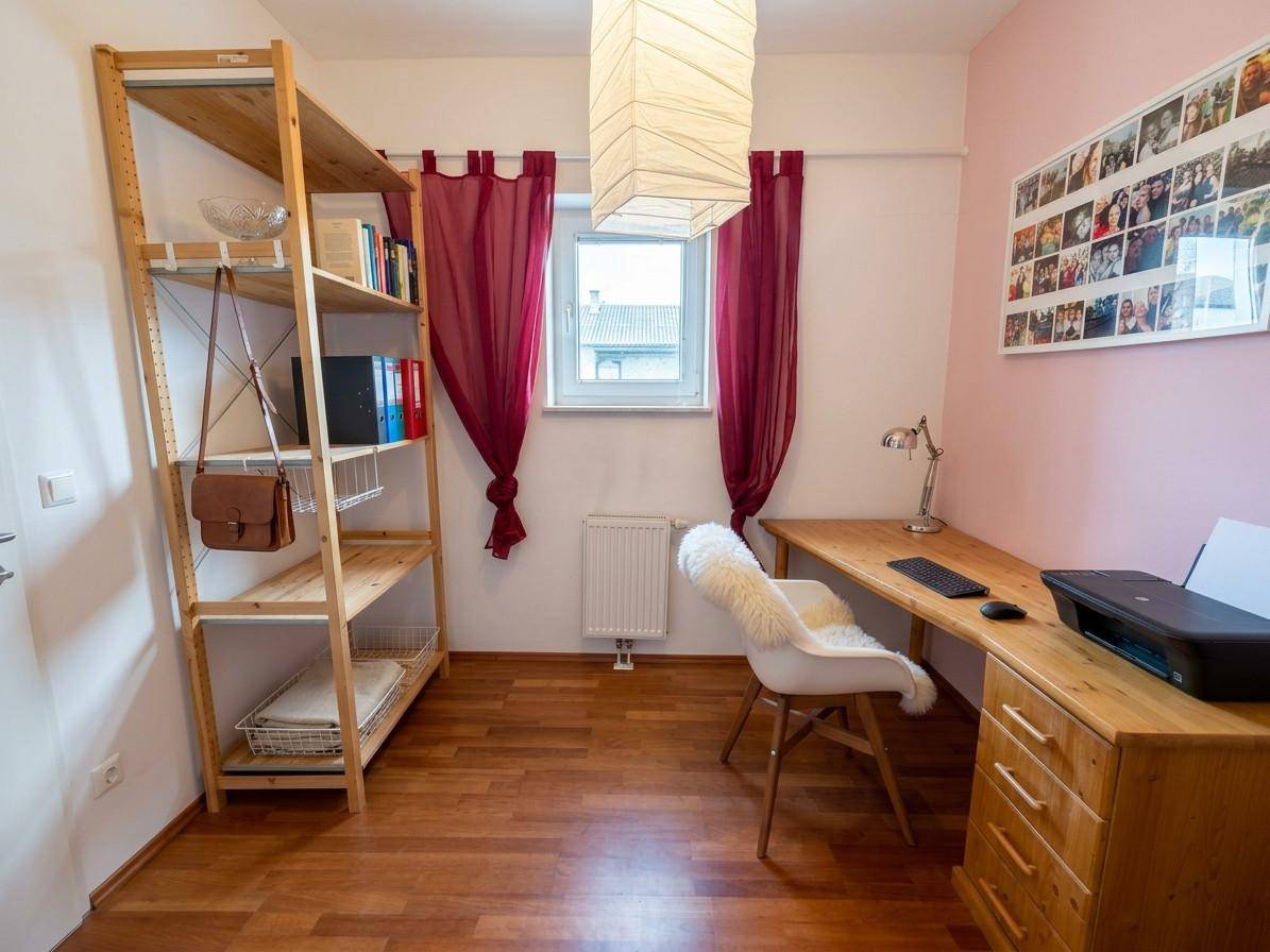 Helles Arbeitszimmer mit Holzregal, Schreibtisch und Fenster.